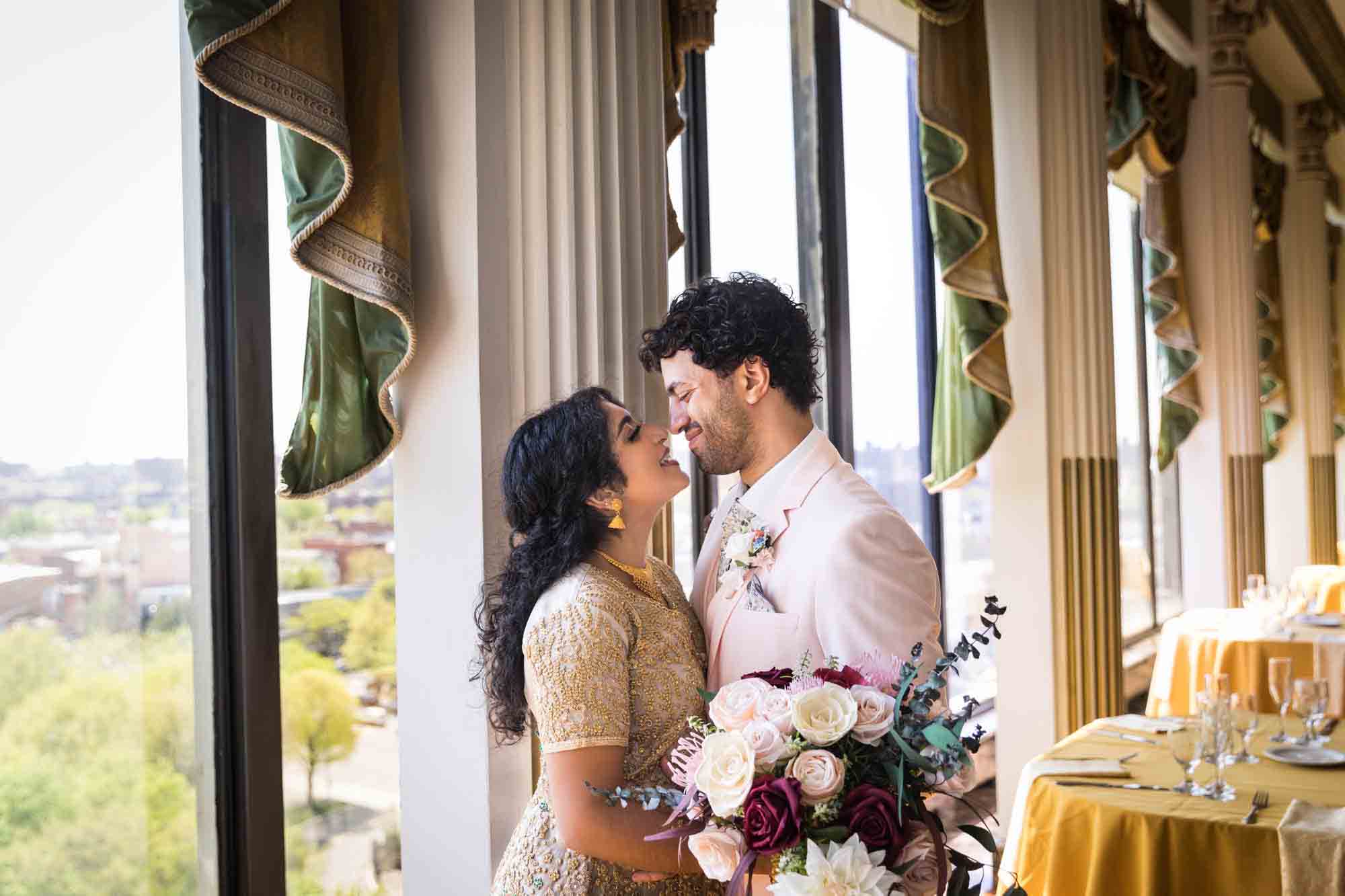 Bride and groom facing each other in front of window in ballroom for an article on Terrace on the Park wedding photo tips
