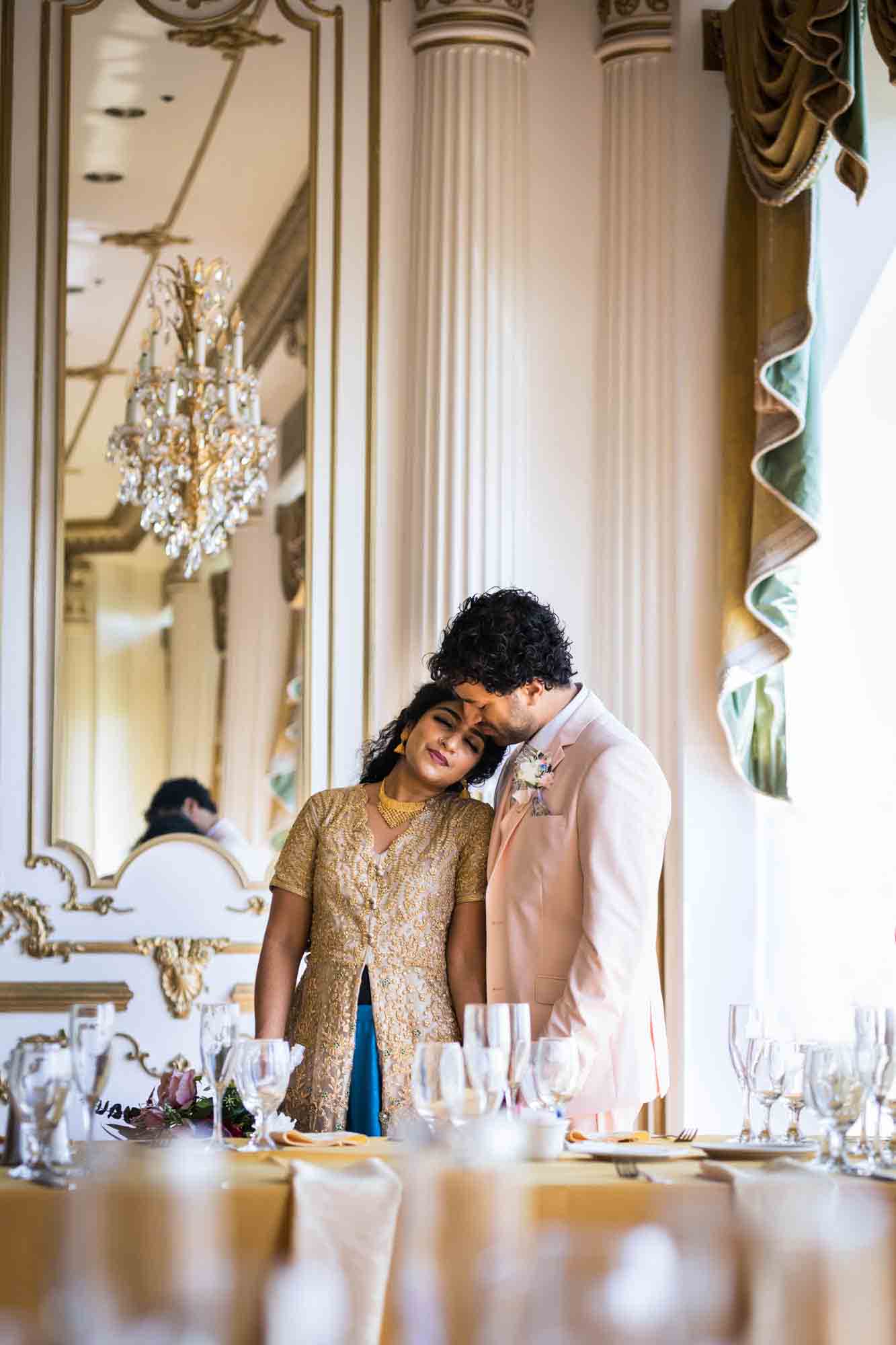 Indian bride and groom hugging behind table in front of mirror during a Terrace on the Park wedding