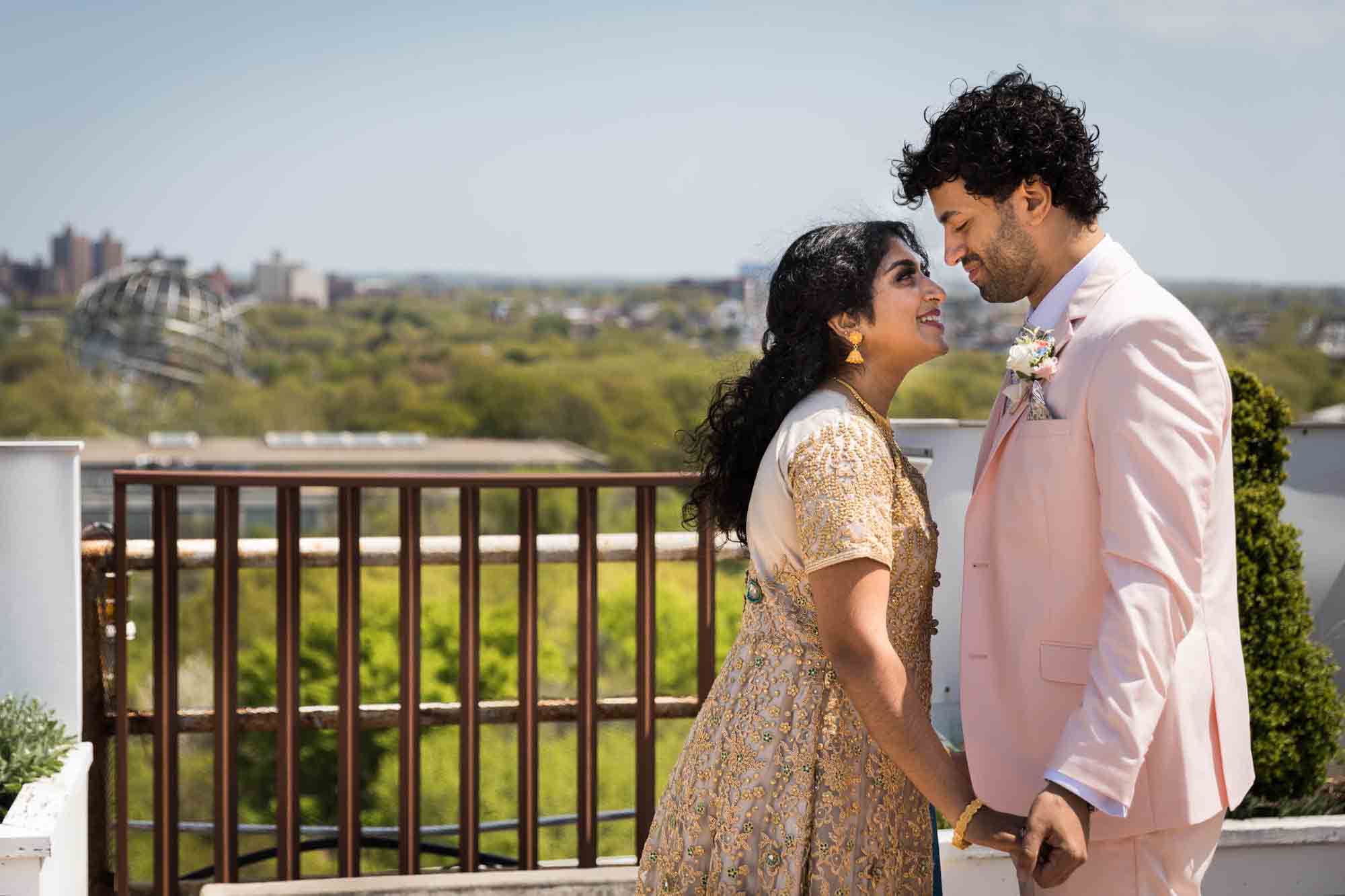 Indian bride and groom holding hands on roof with Unisphere in background during a Terrace on the Park wedding