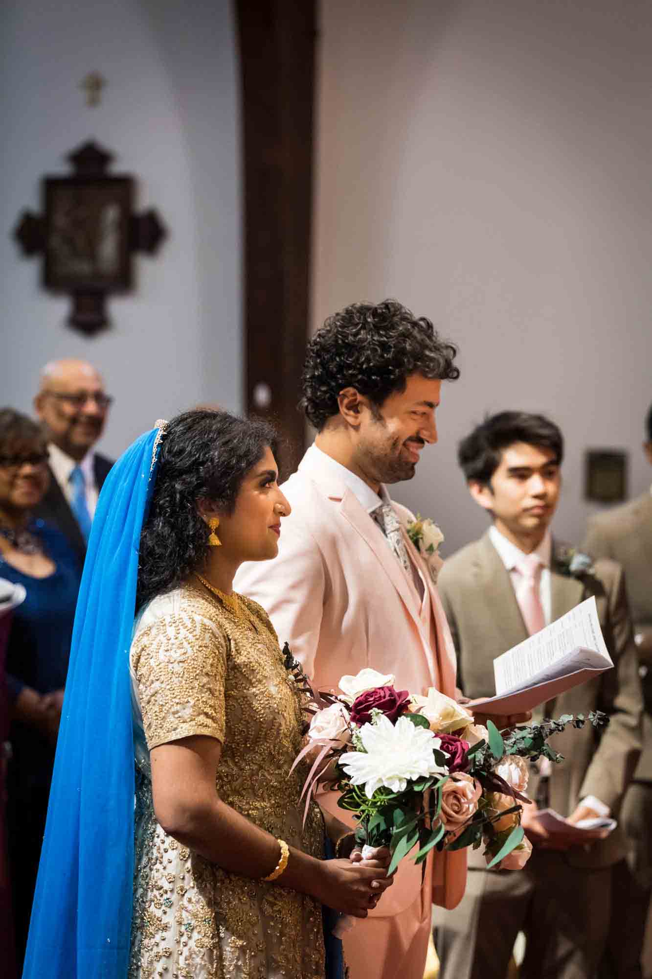 Indian bride and groom standing in front of guests during Syro-Malankara Catholic wedding ceremony