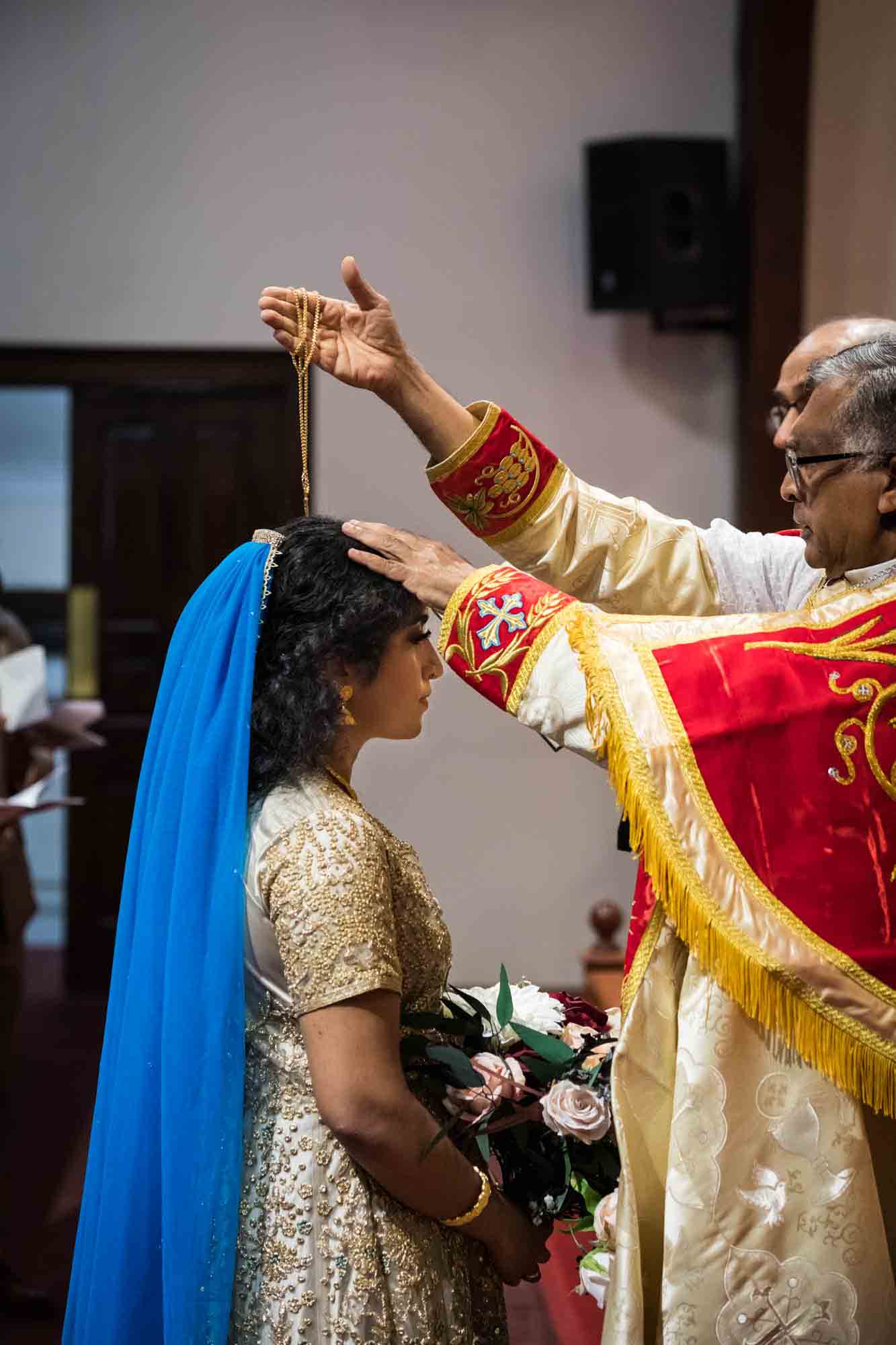 Priest blessing Indian bride with gold necklace during Syro-Malankara Catholic wedding ceremony