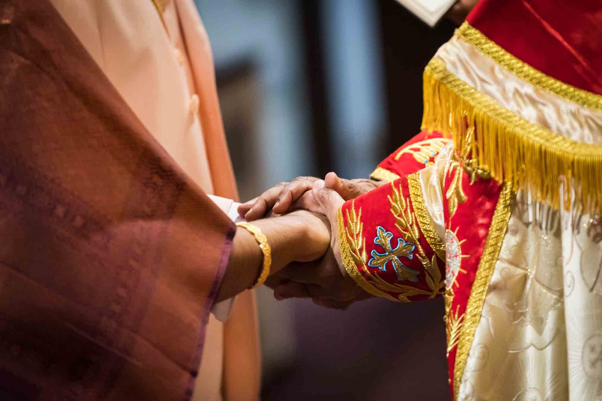 Close up of priest blessing bride and groom's hands during Syro-Malankara Catholic wedding ceremony