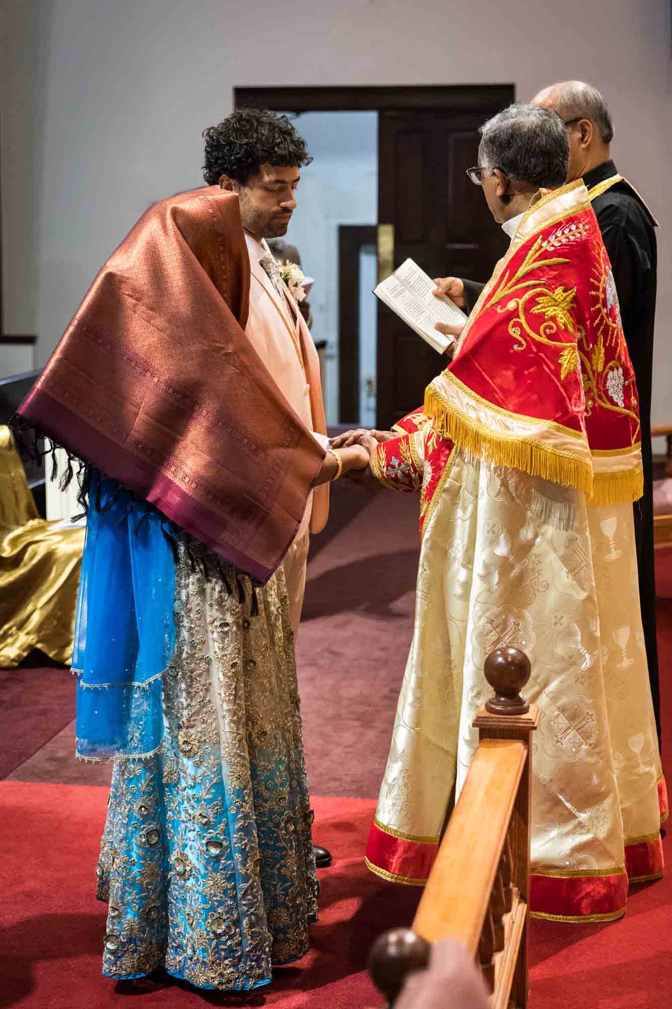 Bride and groom having hands blessed during Syro-Malankara Catholic wedding ceremony