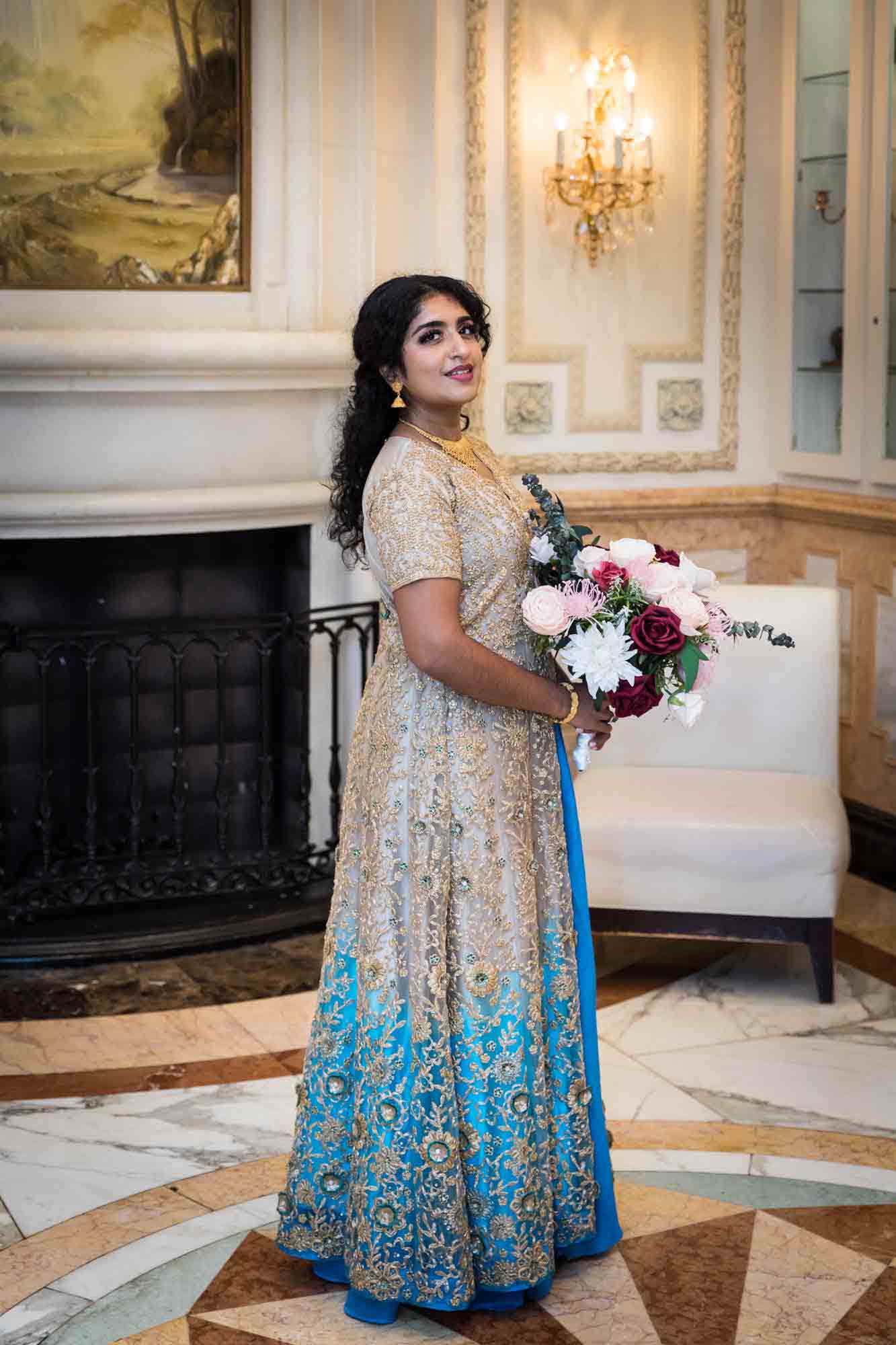 Indian bride wearing gold and blue dress holding flower bouquet during a Terrace on the Park wedding