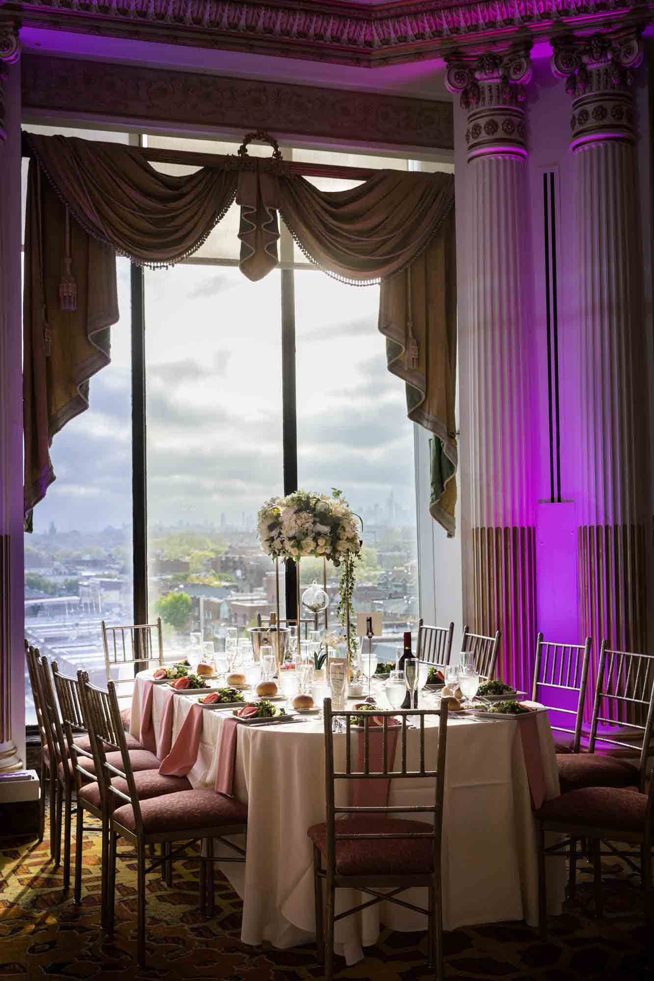 Table in front of window set with glasses and floral centerpiece during a Terrace on the Park wedding