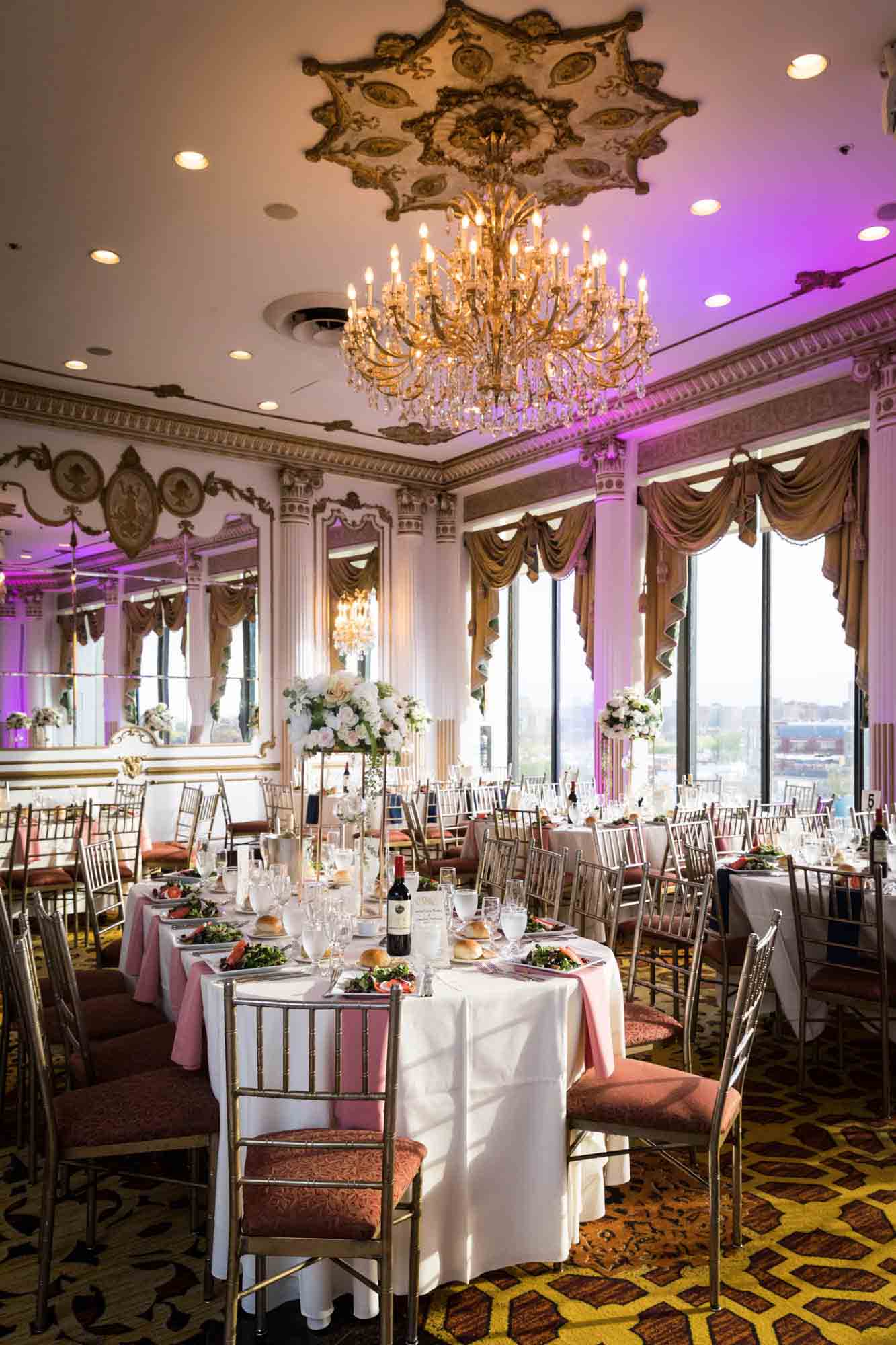Tables set with glasses under gold chandelier during a Terrace on the Park wedding
