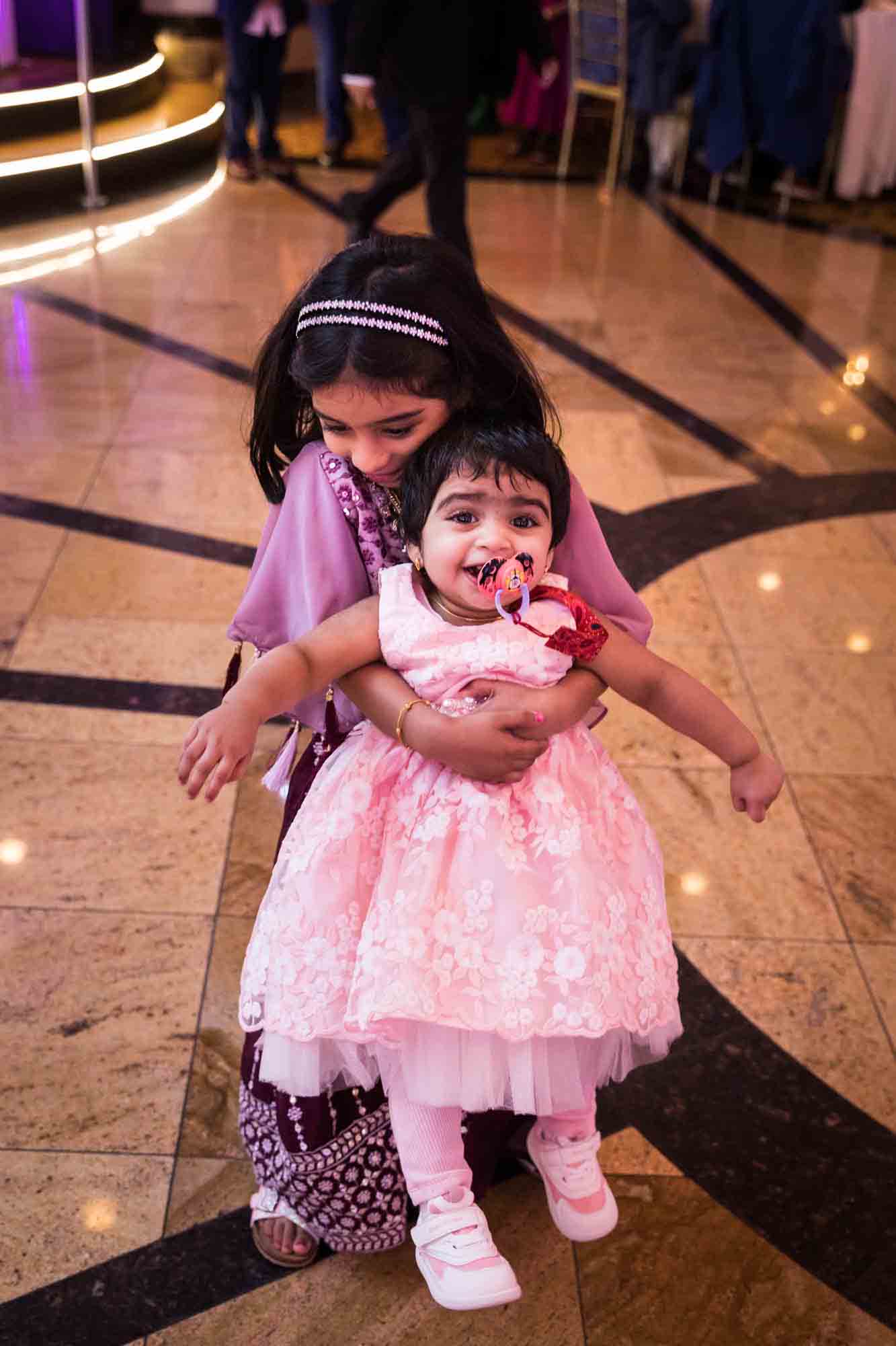 Little girl holding toddler wearing light pink dress during a Terrace on the Park wedding
