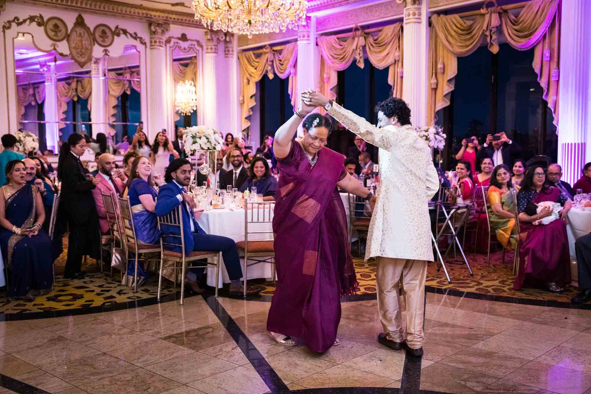 Groom dancing with mother wearing a maroon sari during a Terrace on the Park wedding