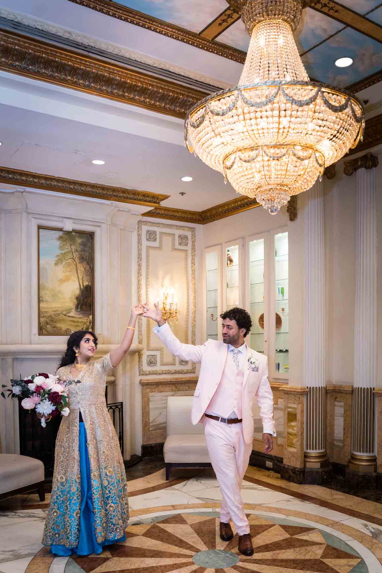 Indian bride and groom dancing under gigantic chandelier during a Terrace on the Park wedding