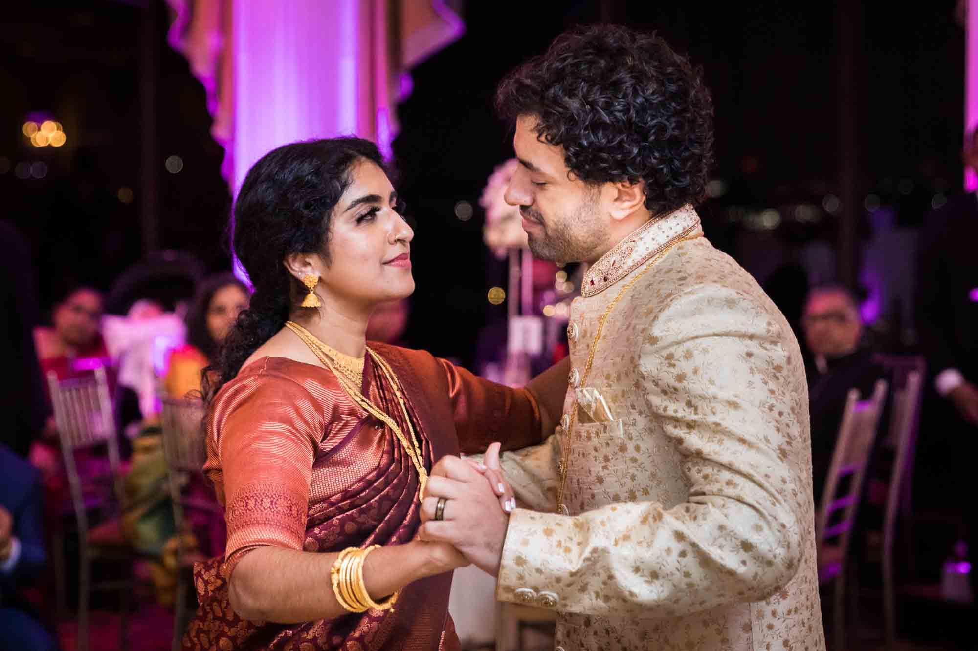 First dance of Indian bride wearing rust colored sari and groom wearing gold tunic for an article on Terrace on the Park wedding photo tips