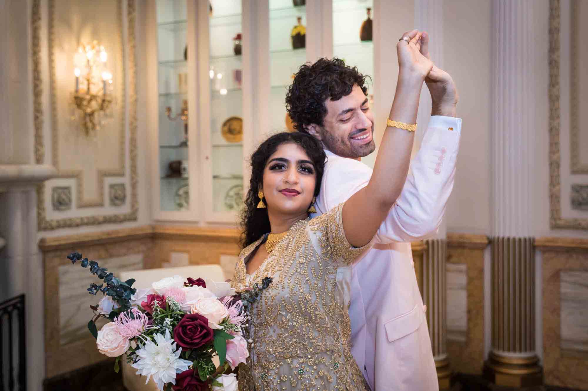 Indian bride and groom dancing while holding flower bouquet during a Terrace on the Park wedding