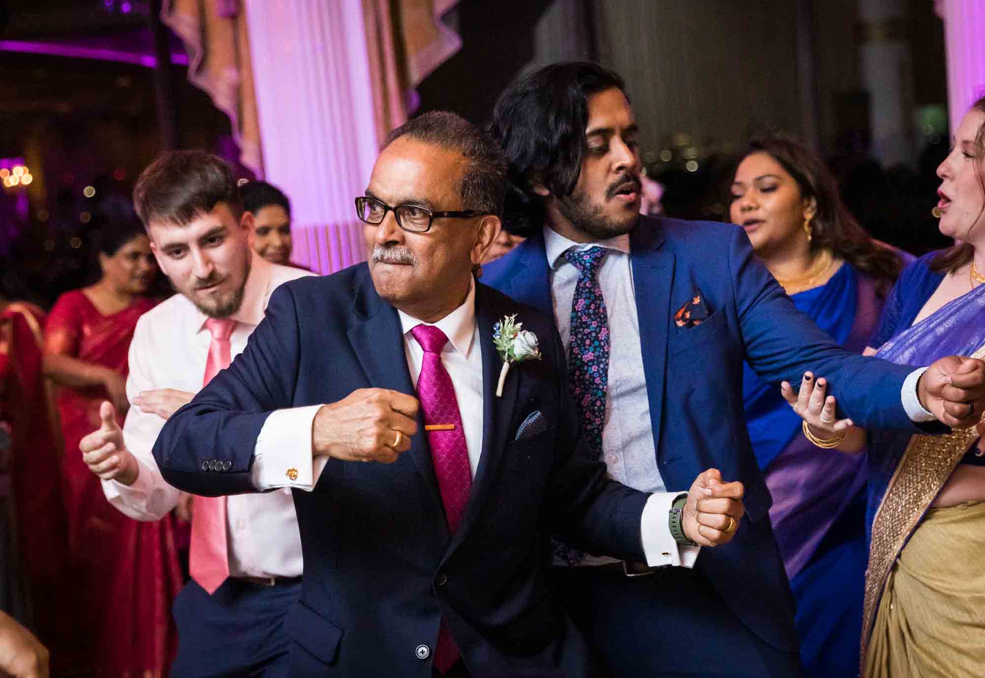 Older man and two young men dance on dance floor for an article on Terrace on the Park wedding photo tips