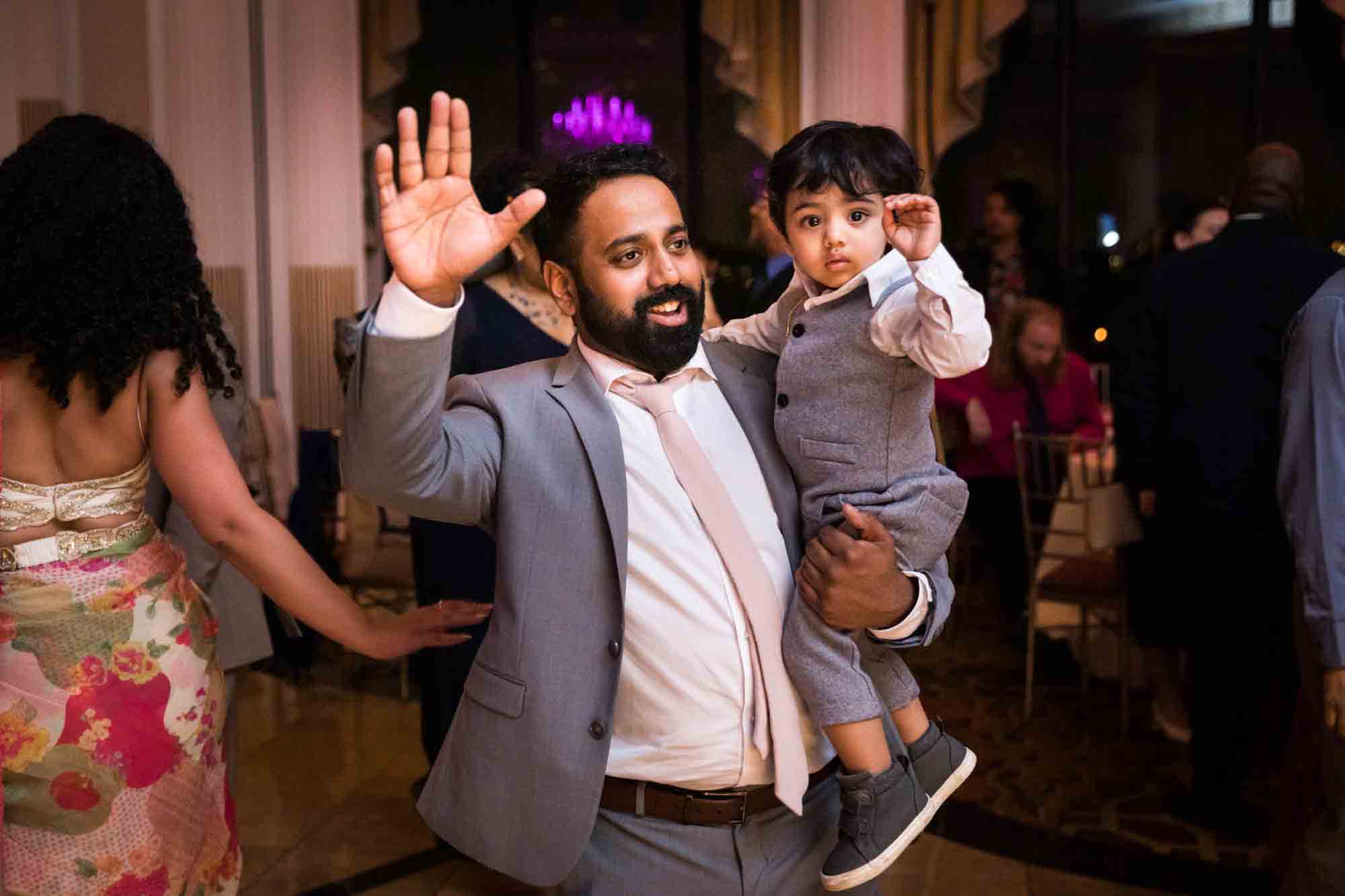 Father holding young son dancing with arms raised for an article on Terrace on the Park wedding photo tips