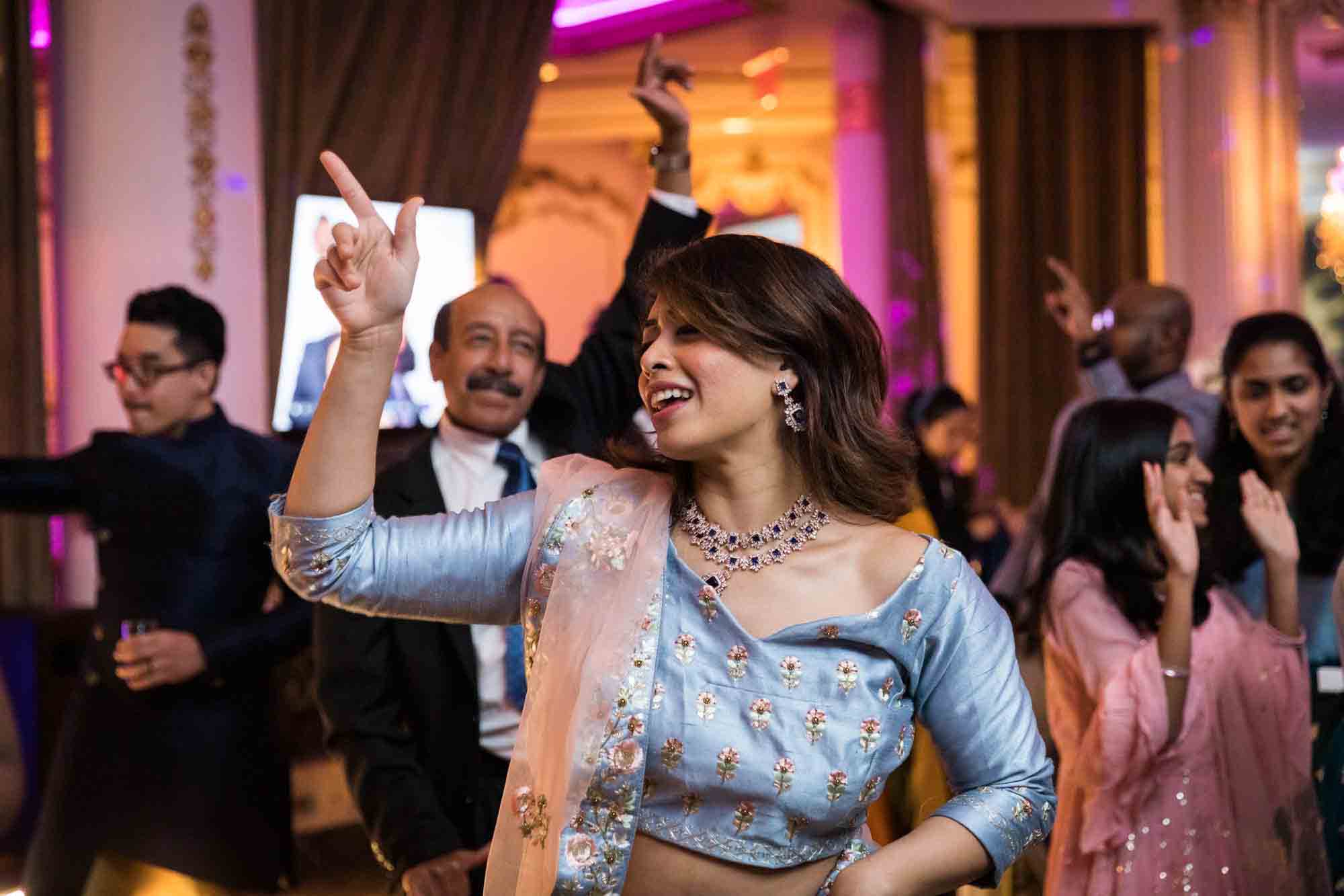 Indian woman wearing light blue sari dancing with hand raised for an article on Terrace on the Park wedding photo tips