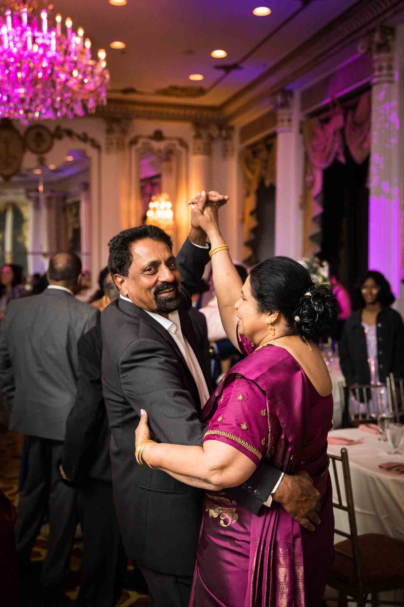 Older Indian couple dancing under chandelier for an article on Terrace on the Park wedding photo tips