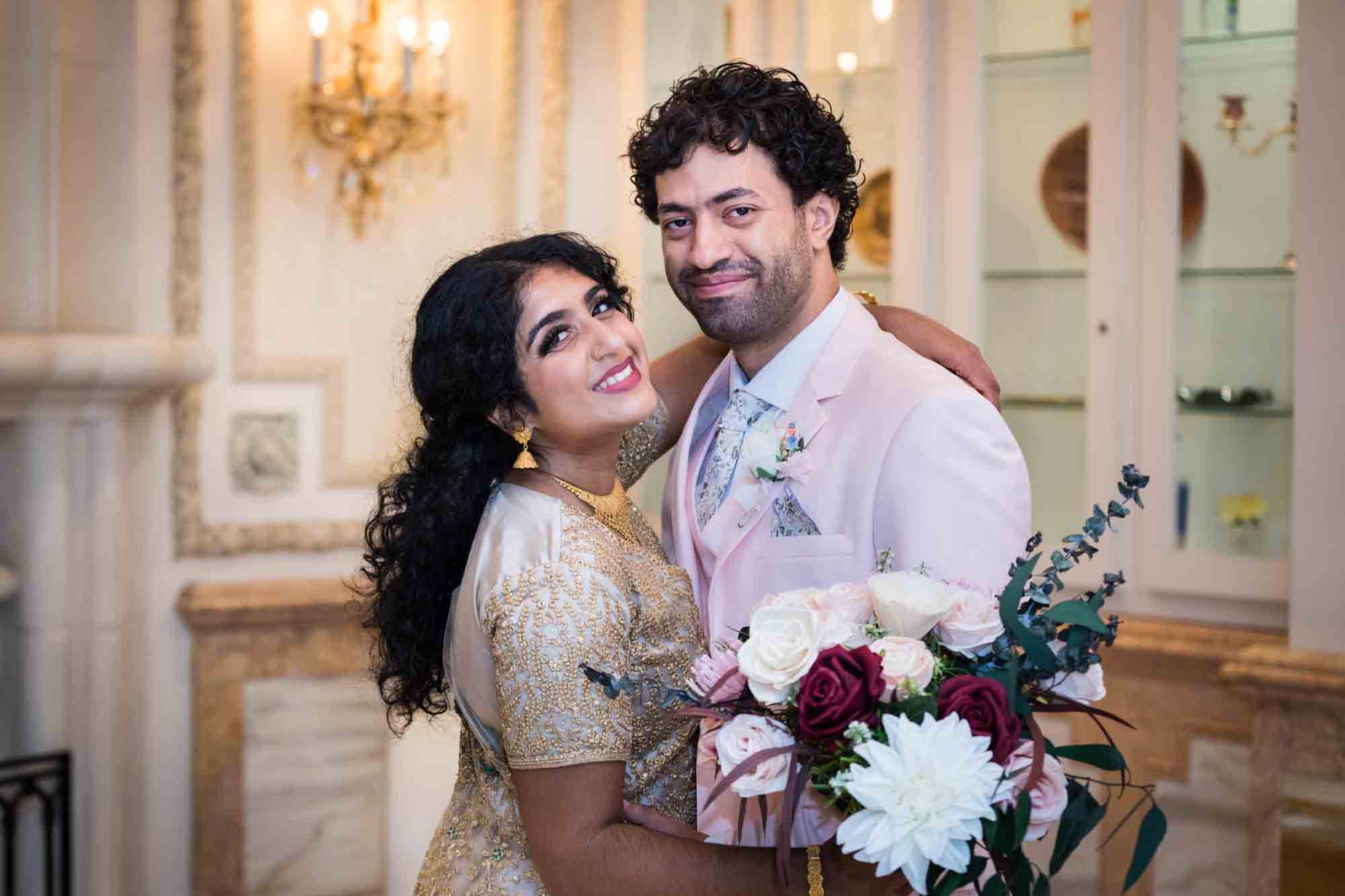 Indian bride and groom hugging while holding flower bouquet during a Terrace on the Park wedding