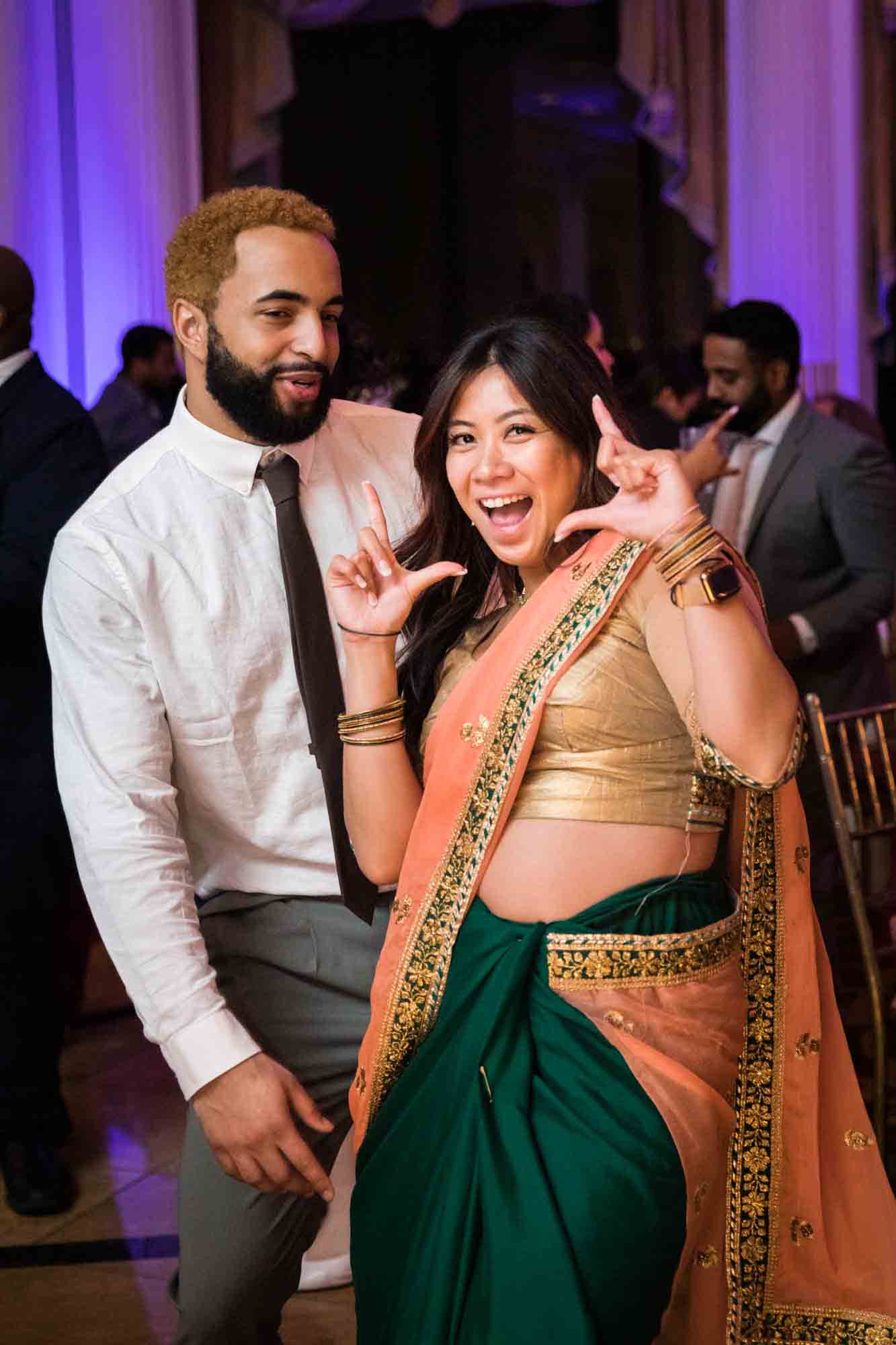 Asian woman wearing peach and green sari dancing with man in white shirt and tie for an article on Terrace on the Park wedding photo tips