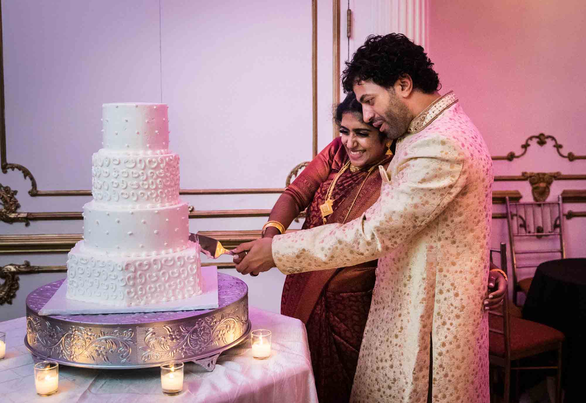Indian bride and groom cutting into tiered white wedding cake for an article on Terrace on the Park wedding photo tips