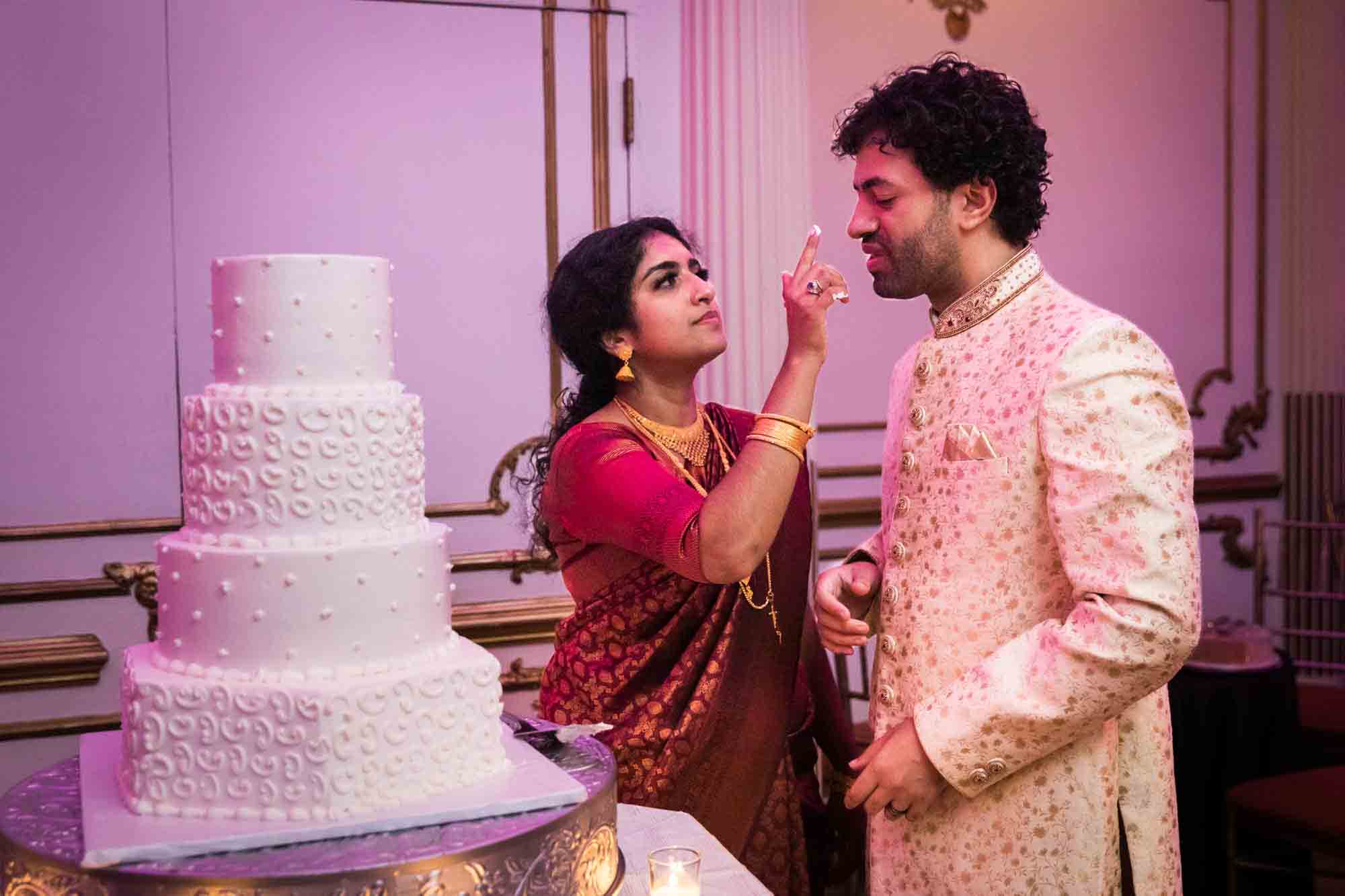 Indian bride about to put a fingertip full of frosting on groom's face for an article on Terrace on the Park wedding photo tips