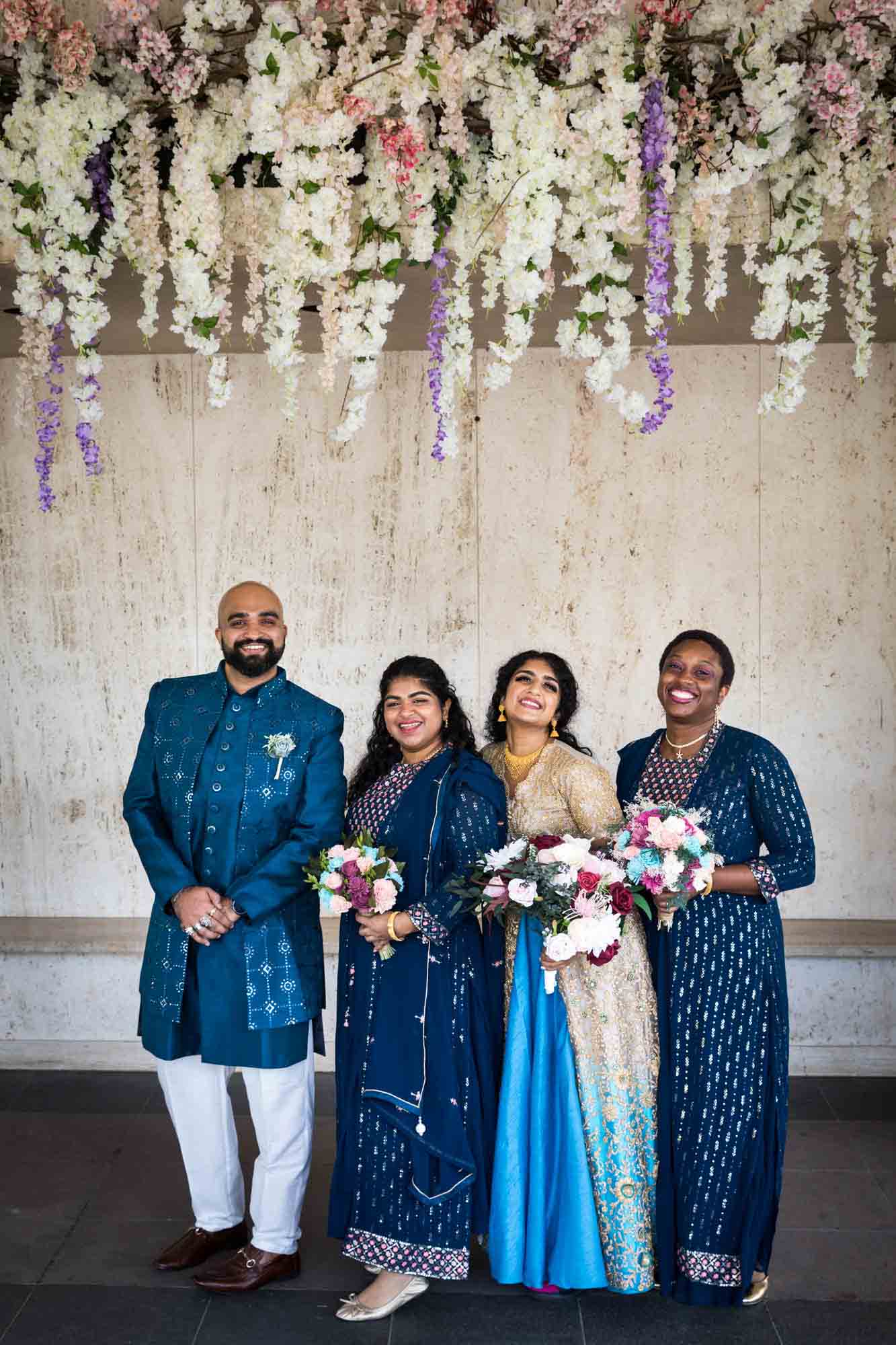 Indian bride and bridal party standing under trailing flowers for an article on Terrace on the Park wedding photo tips