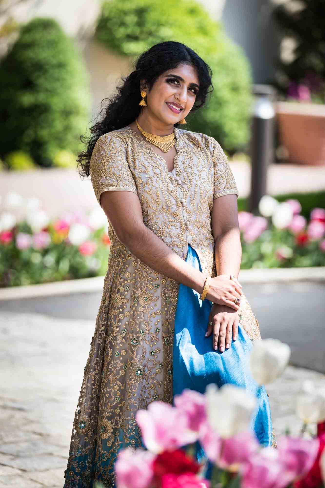 Indian bride wearing gold dress standing behind tulips for an article on Terrace on the Park wedding photo tips