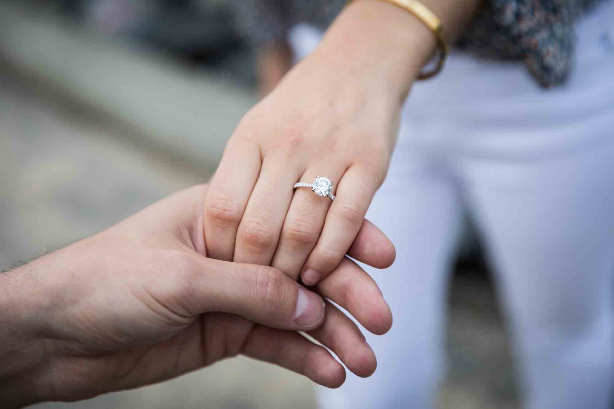 Close up of man holding woman's hand showing large diamond engagement ring