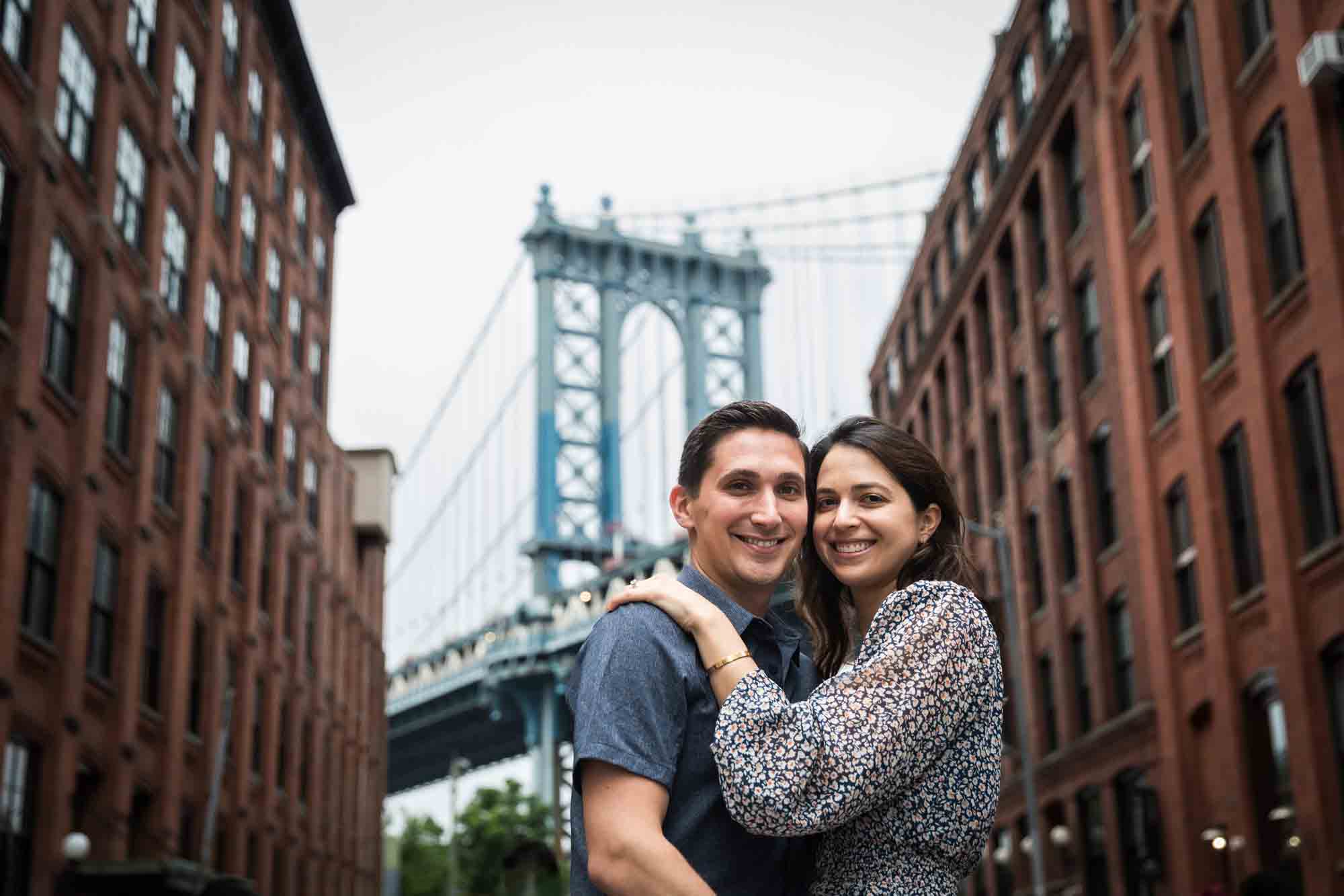 Couple hugging in front of Manhattan Bridge and brick buildings