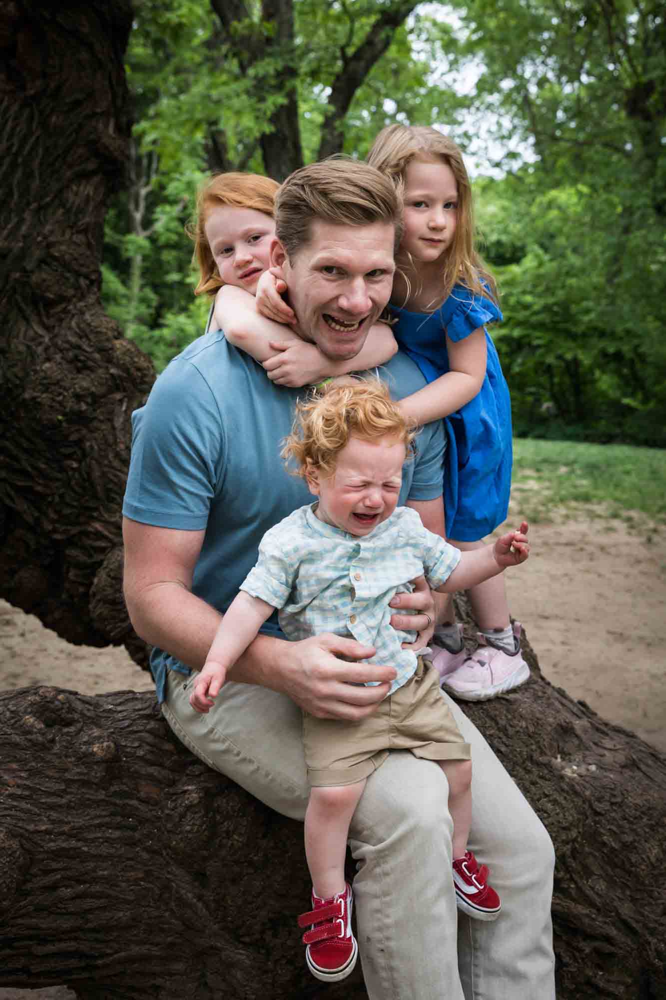 Father with three kids sitting in tree during a Central Park family portrait session