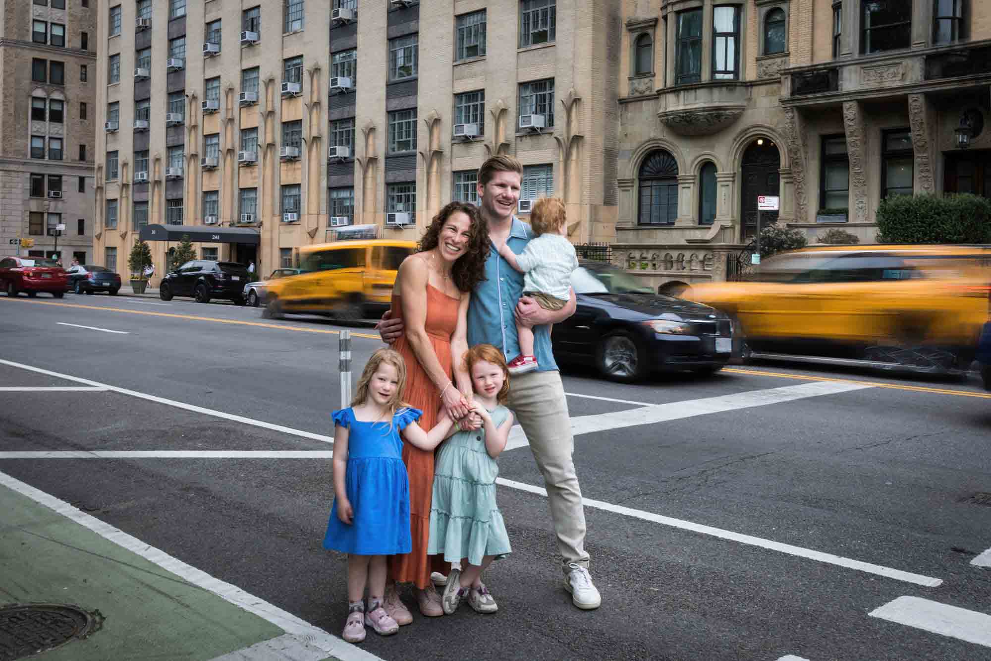Family with three kids in middle of NYC street with taxis going past in blur