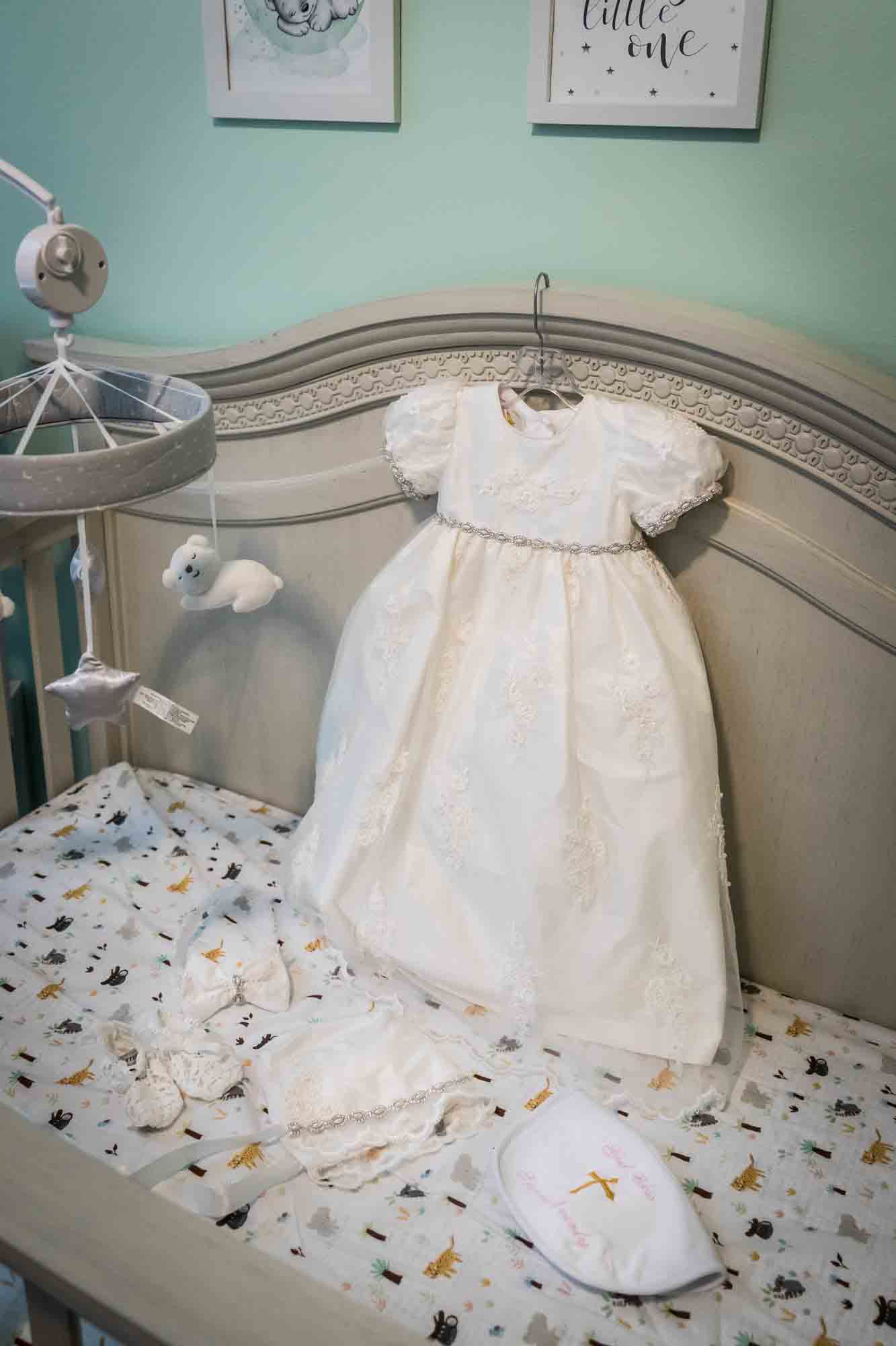 White baptism dress, shoes, and bib lying in crib