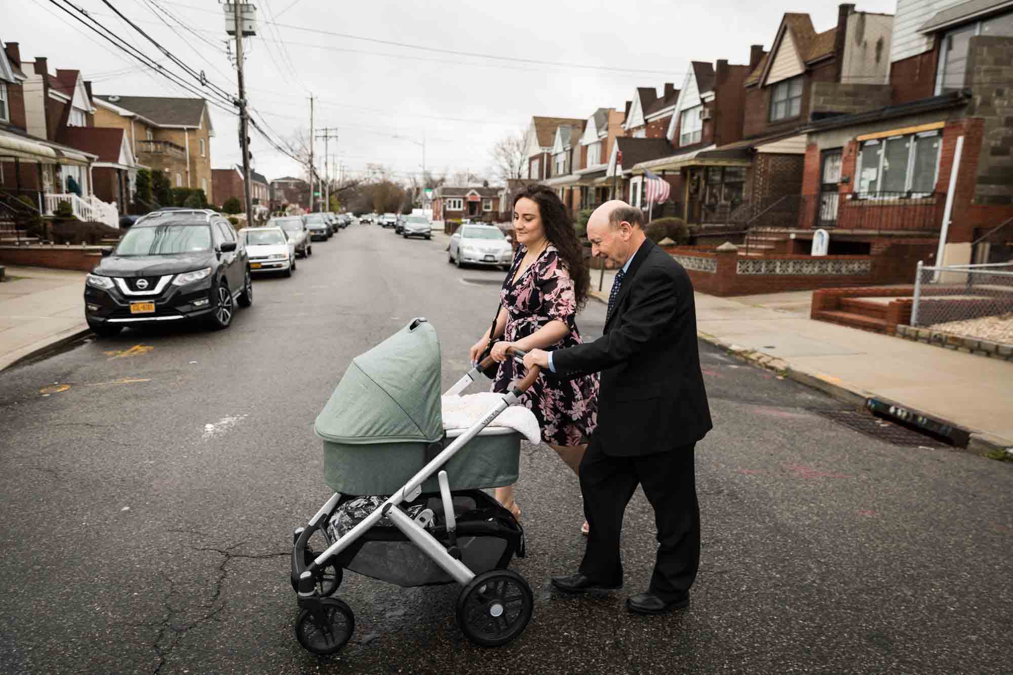 Mother and grandfather pushing baby carriage in middle of street