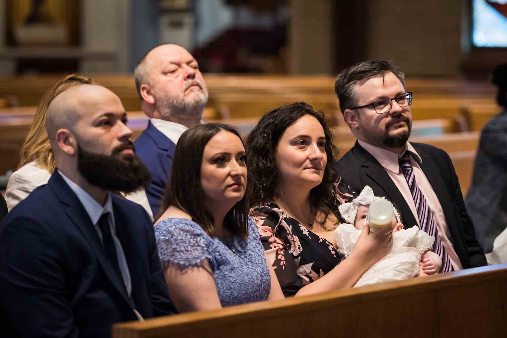 Maspeth baptism photos of family sitting in pew holding baby