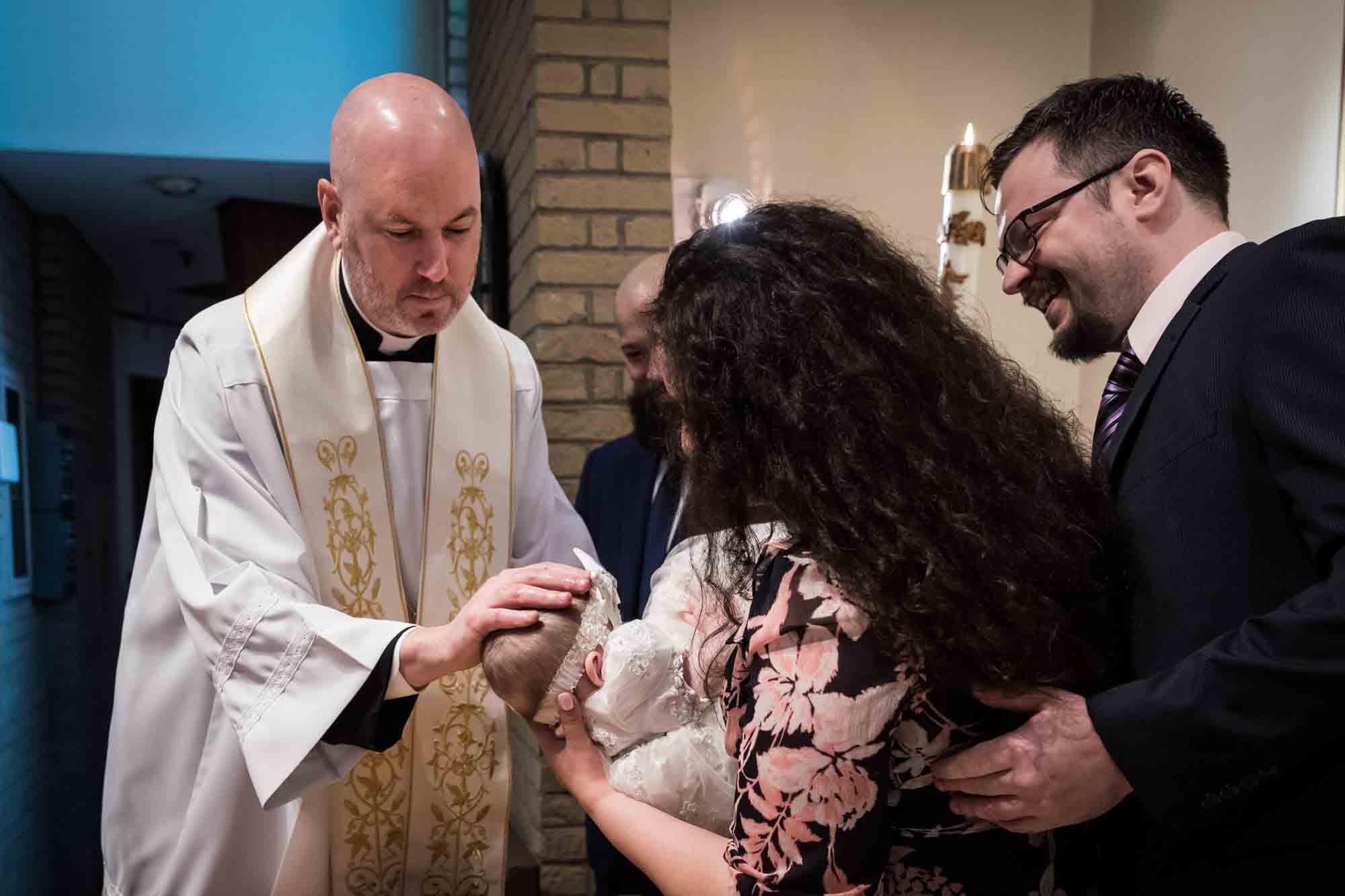 Maspeth baptism photos of priest drying baby's head with family watching