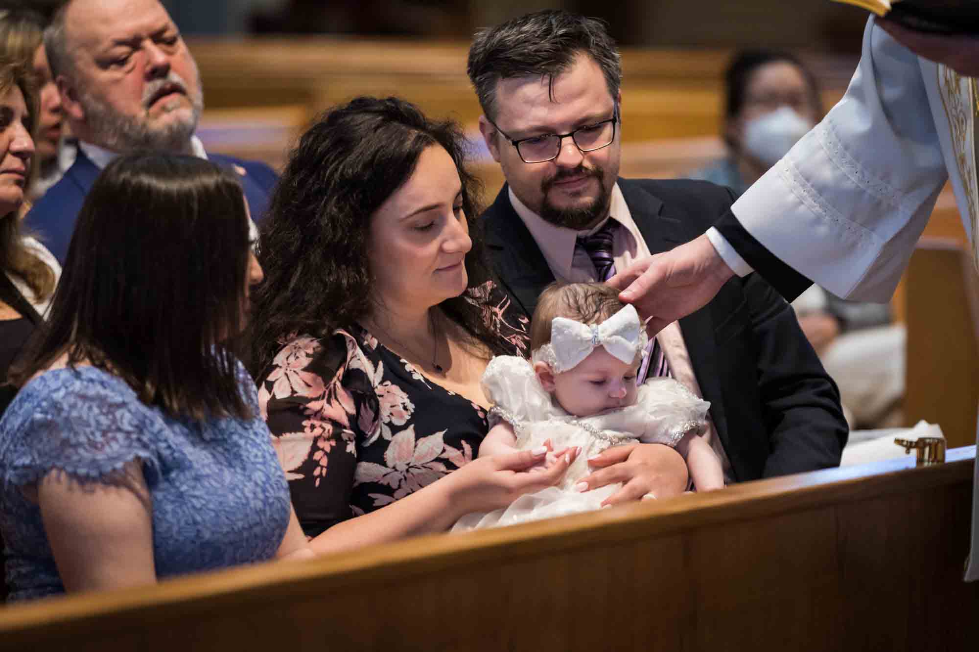 Maspeth baptism photos of priest anointing baby's head with oil 
