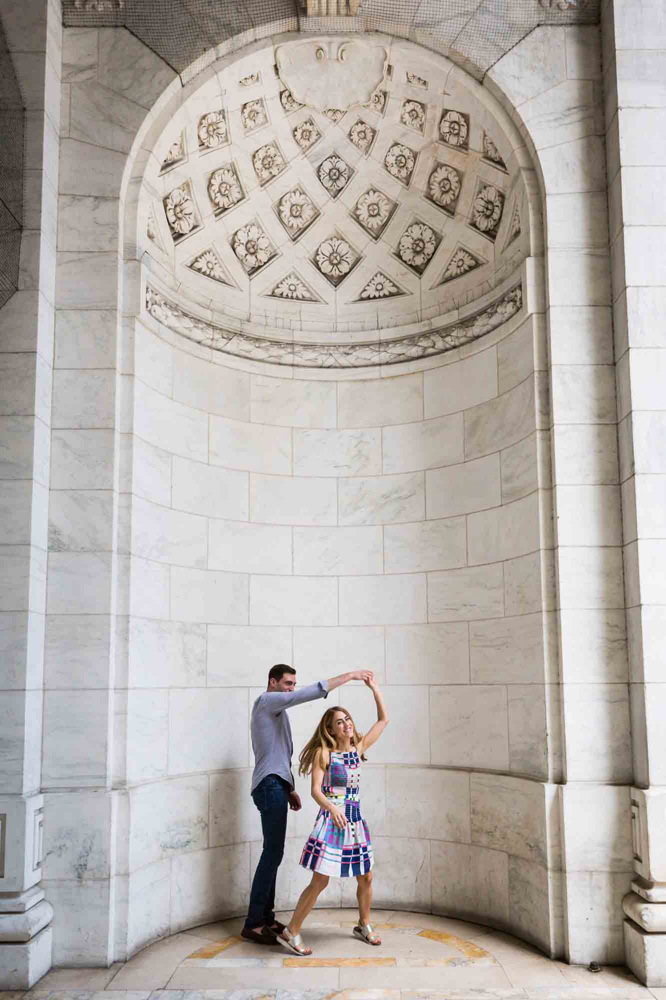 Couple dancing in a marble rotunda during a New York public library engagement photo shoot