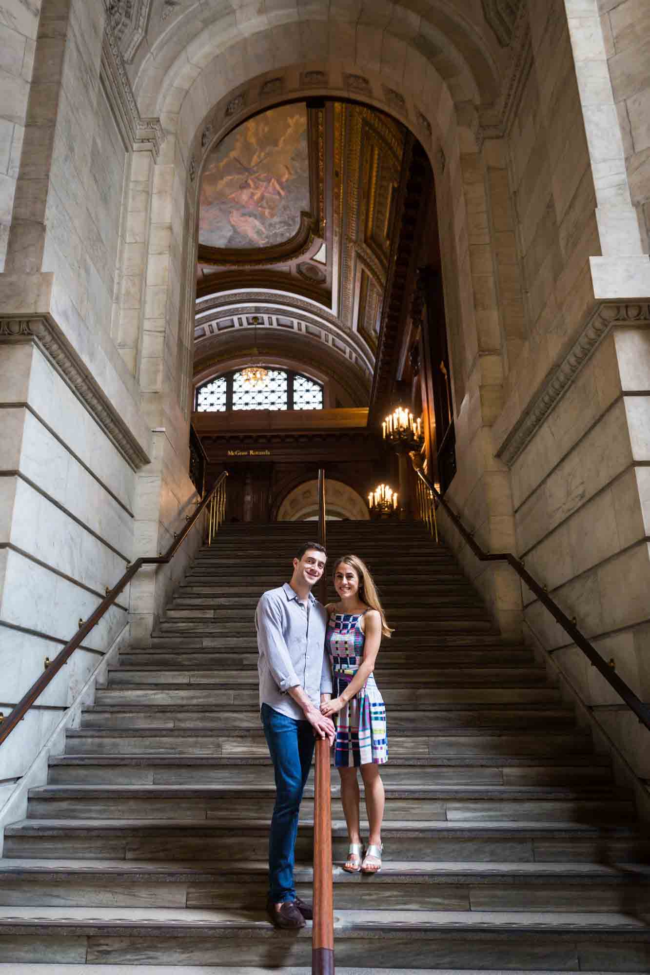 Couple standing together on a marble staircase during a New York public library engagement photo shoot