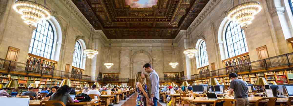 Couple holding hands in the Rose Main Reading Room during a New York public library engagement photo shoot