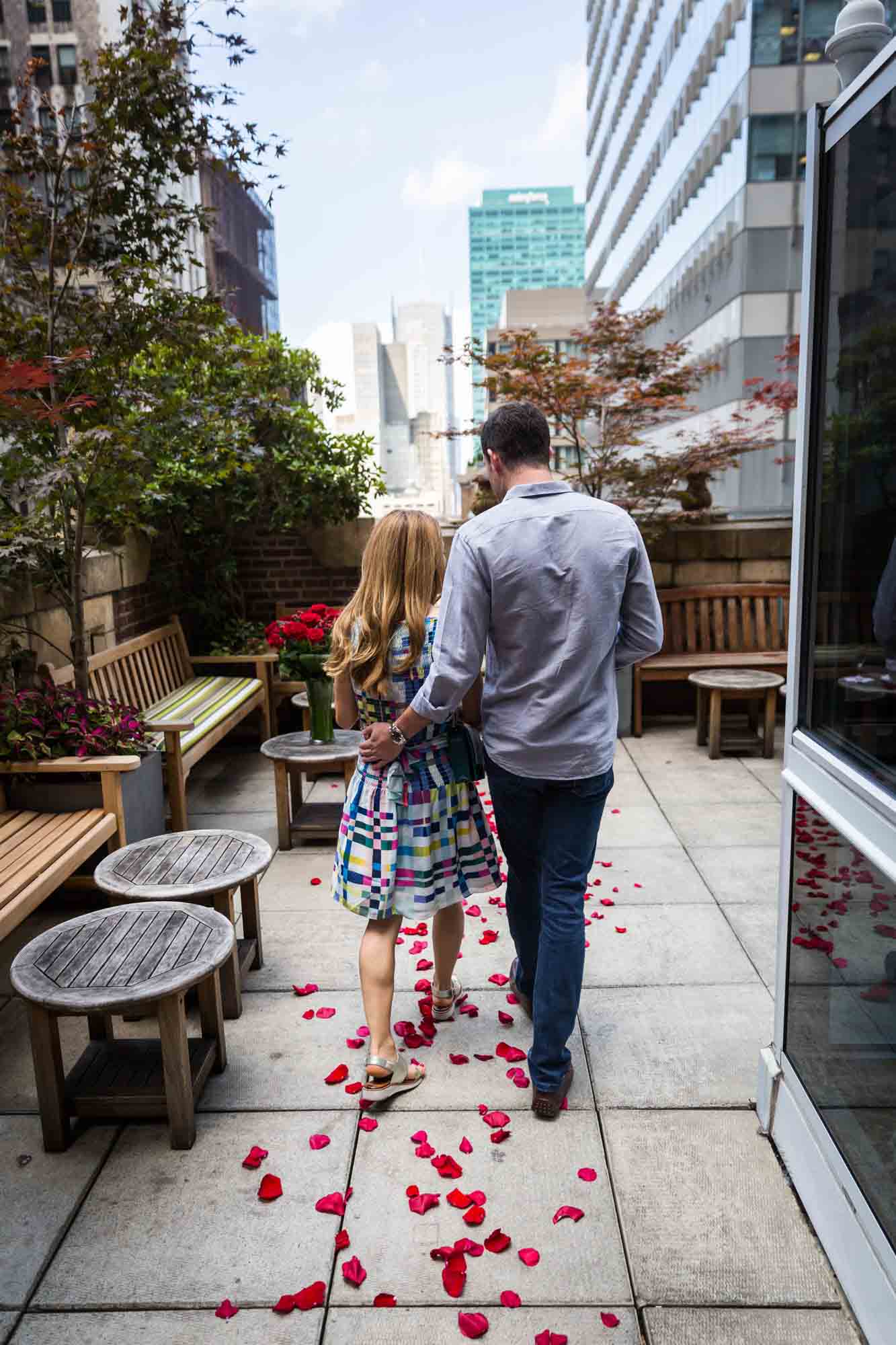 Couple walking over red rose petals on the patio of the Library Hotel