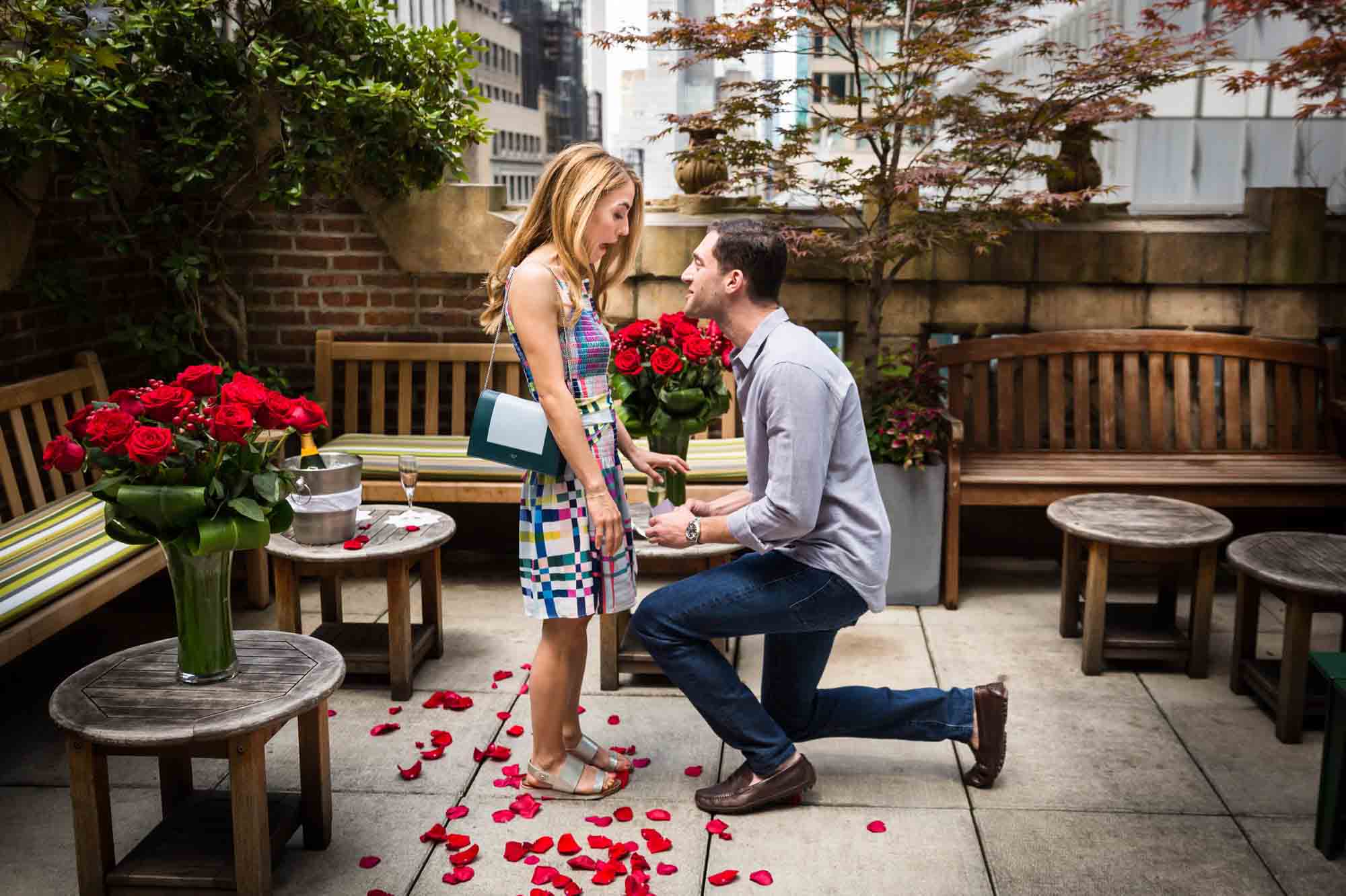 Man on one knee proposing to woman wearing multicolored dress at the Library Hotel
