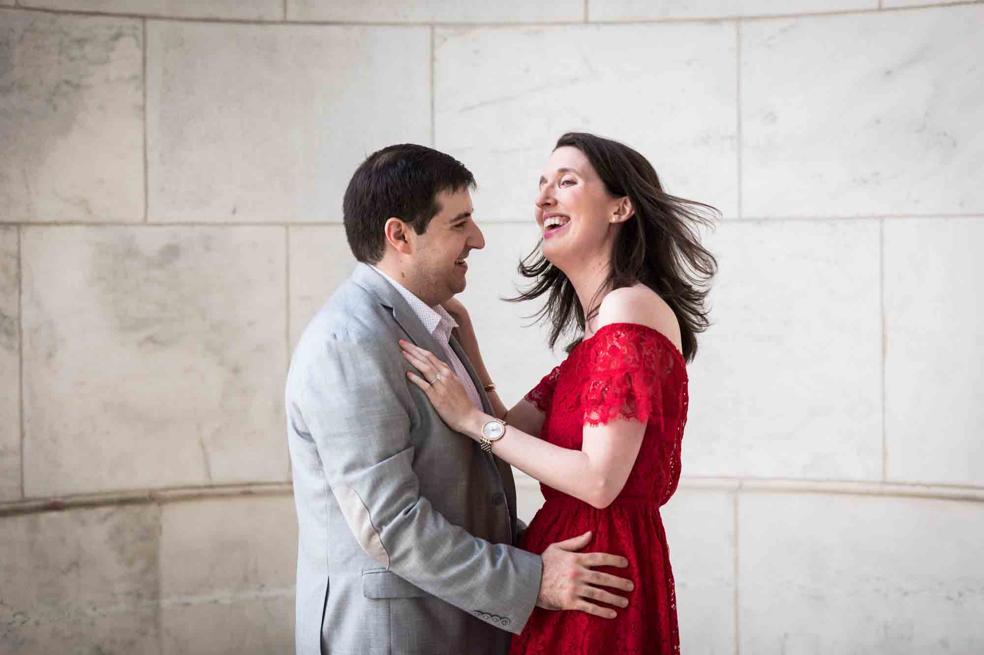 Man dancing in marble alcove with woman wearing red dress during a New York Public Library surprise proposal