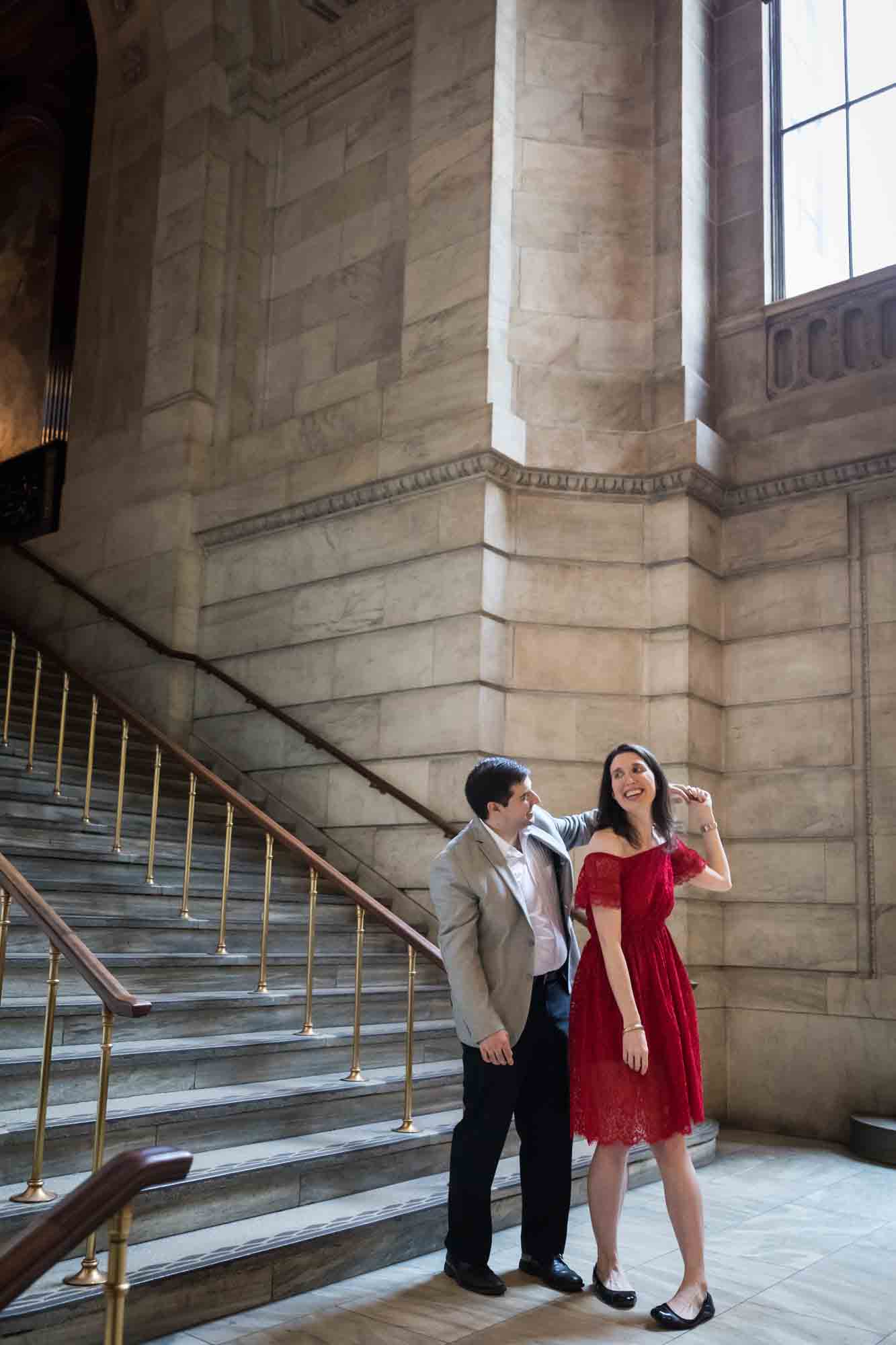 Couple dancing in front of staircase and grey stone wall during a New York Public Library surprise proposal