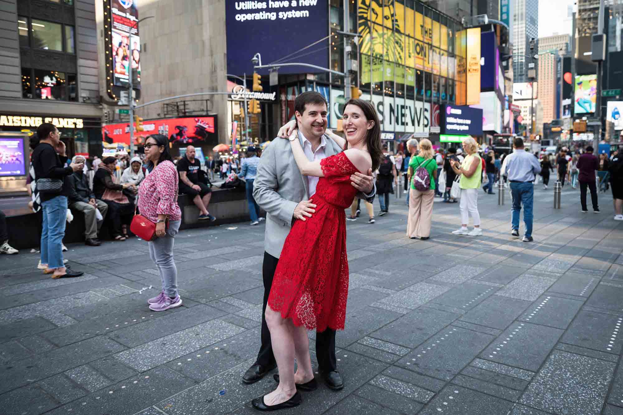 Woman wearing red dress dancing with man in Times Square