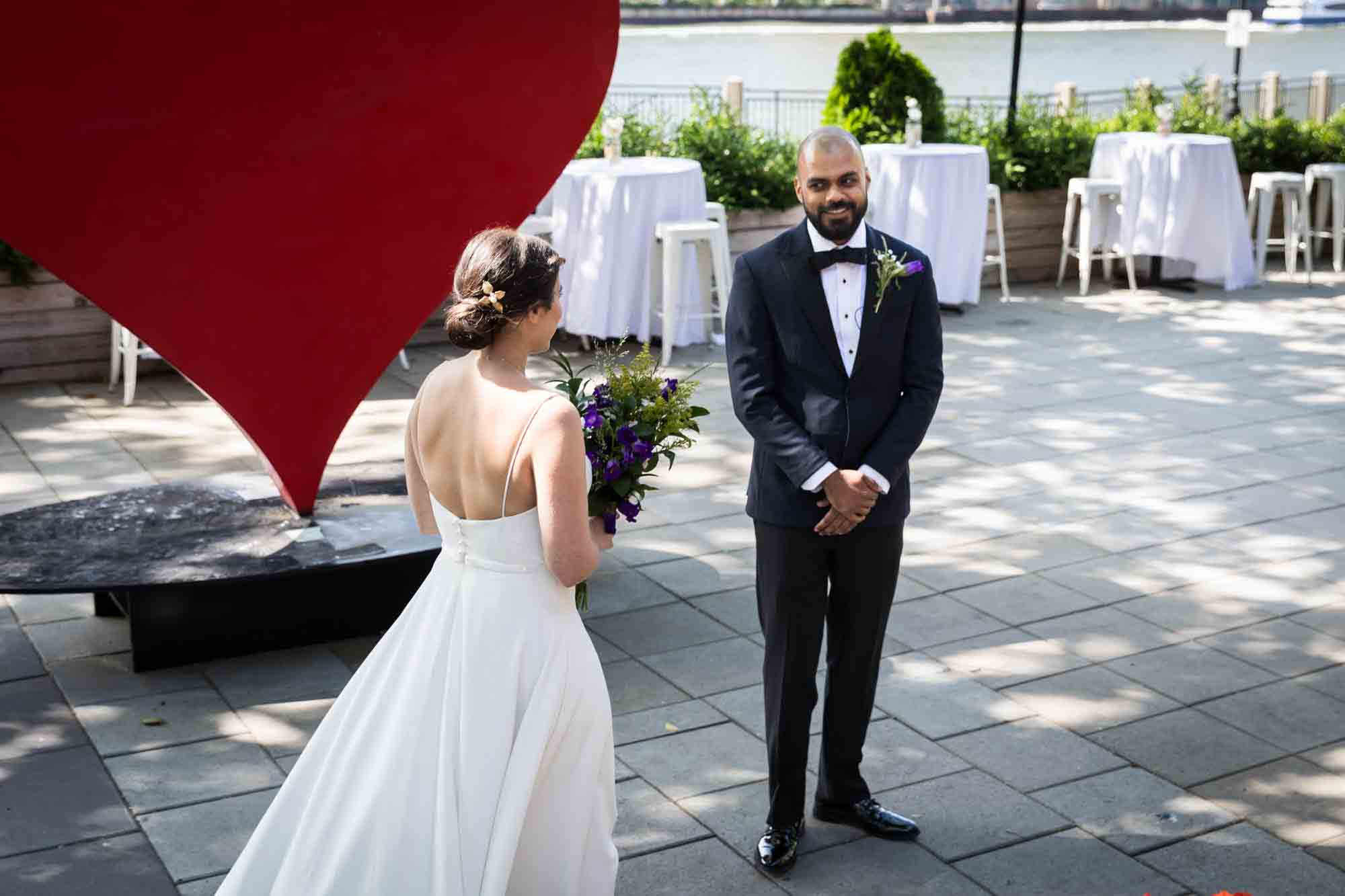 Groom wearing tux seeing bride in dress for first time on outdoor patio at a Sanctuary Roosevelt Island wedding