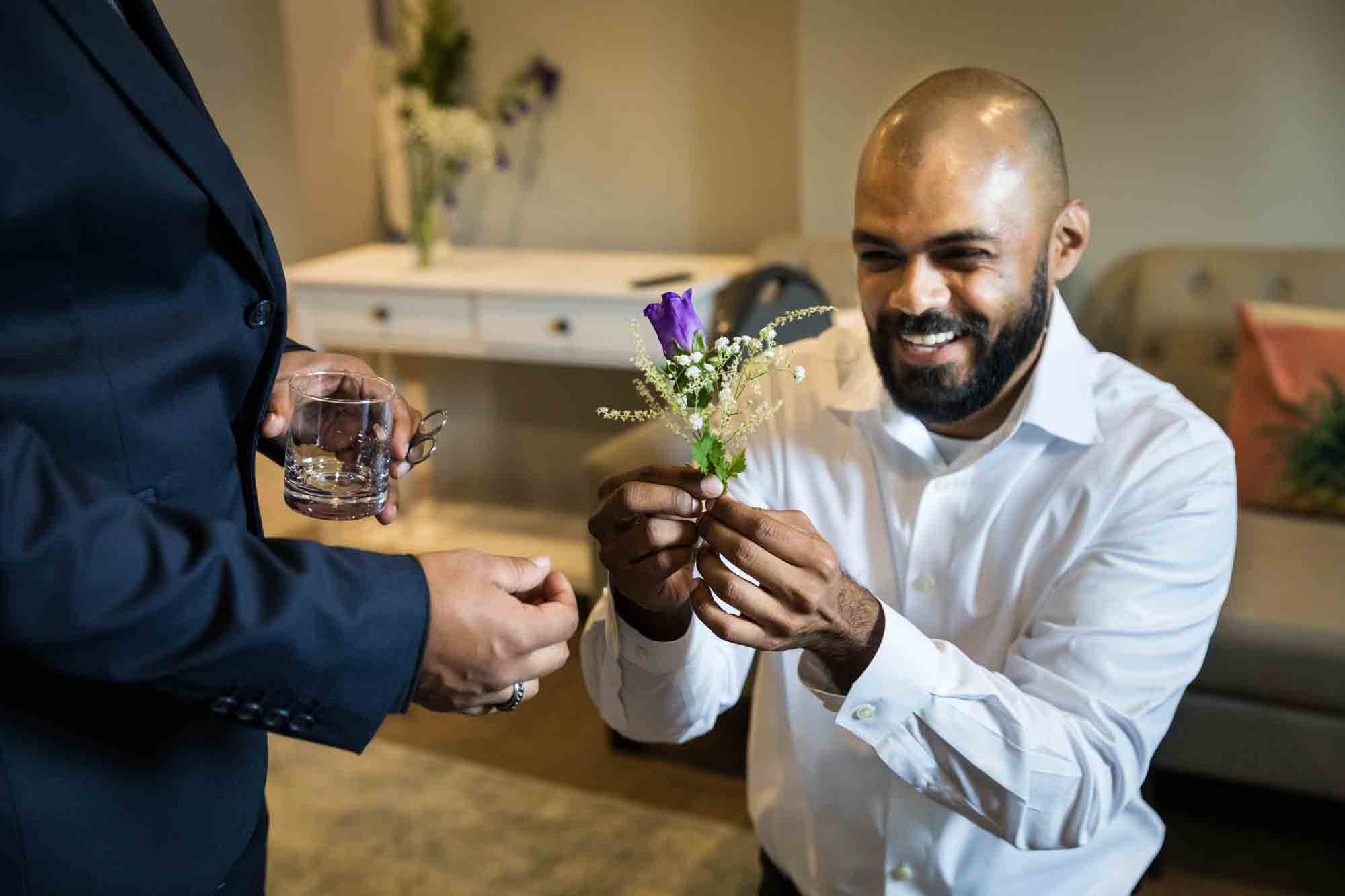 Bald groom holding small bouquet of purple and white flowers at a Sanctuary Roosevelt Island wedding