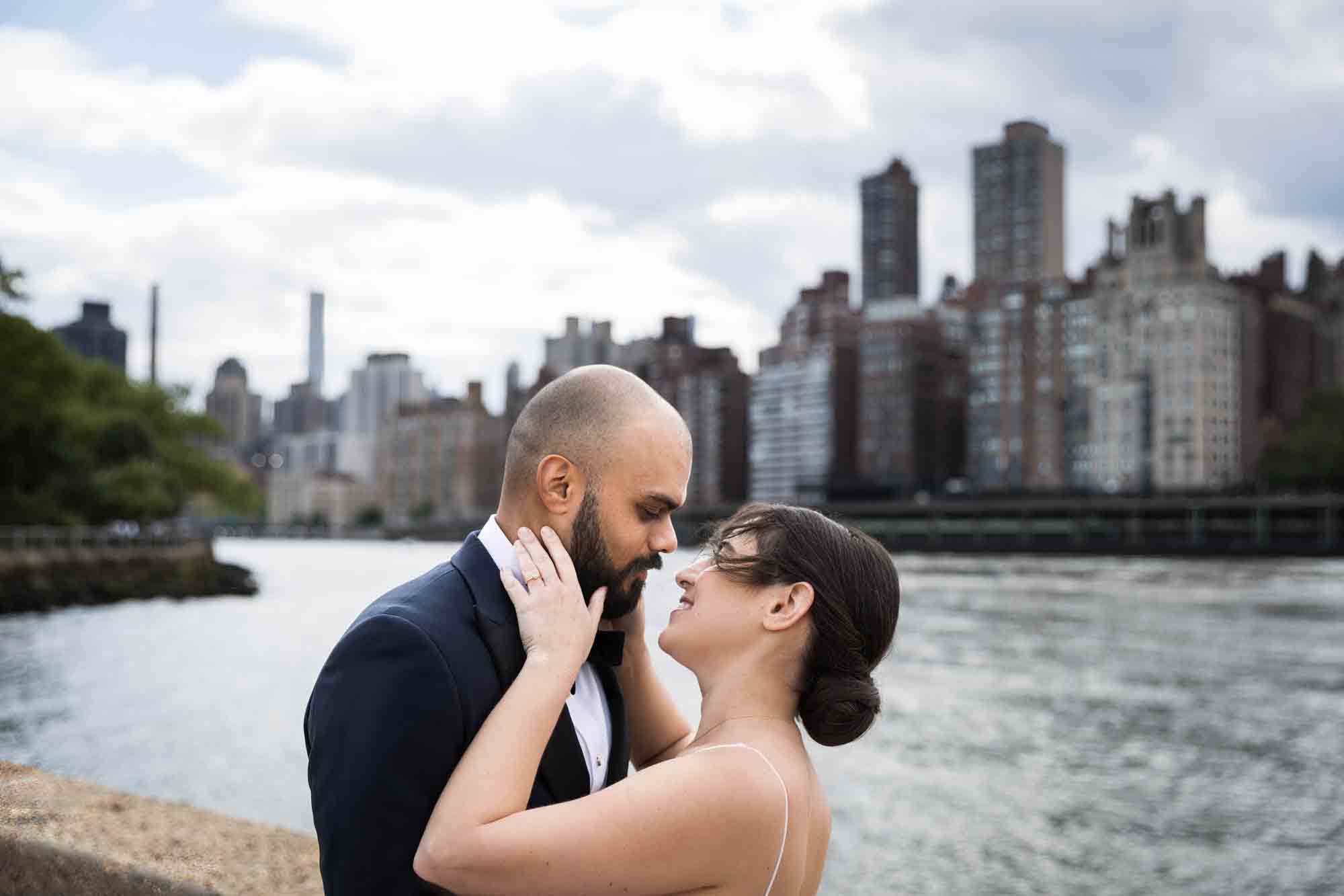 Bride and groom about to kiss in front of NYC skyline on Roosevelt Island
