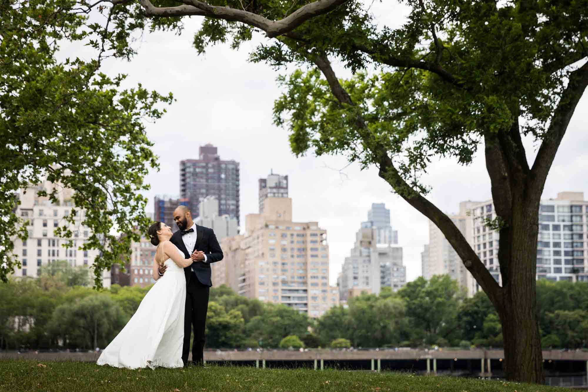 Bride and groom dancing in park in front of NYC skyline on Roosevelt Island