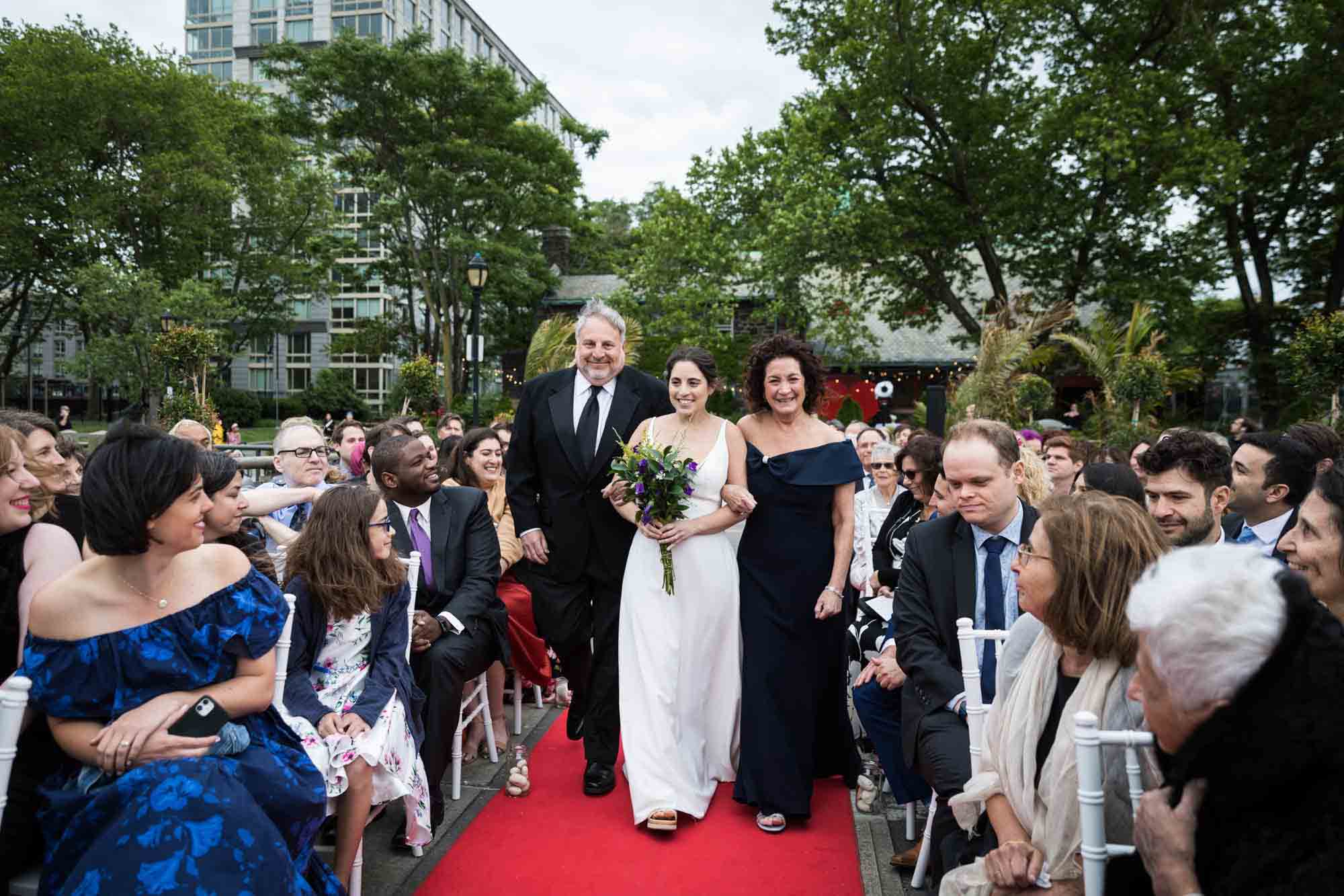 Bride and parents walking down aisle in front of guests at a Sanctuary Roosevelt Island wedding