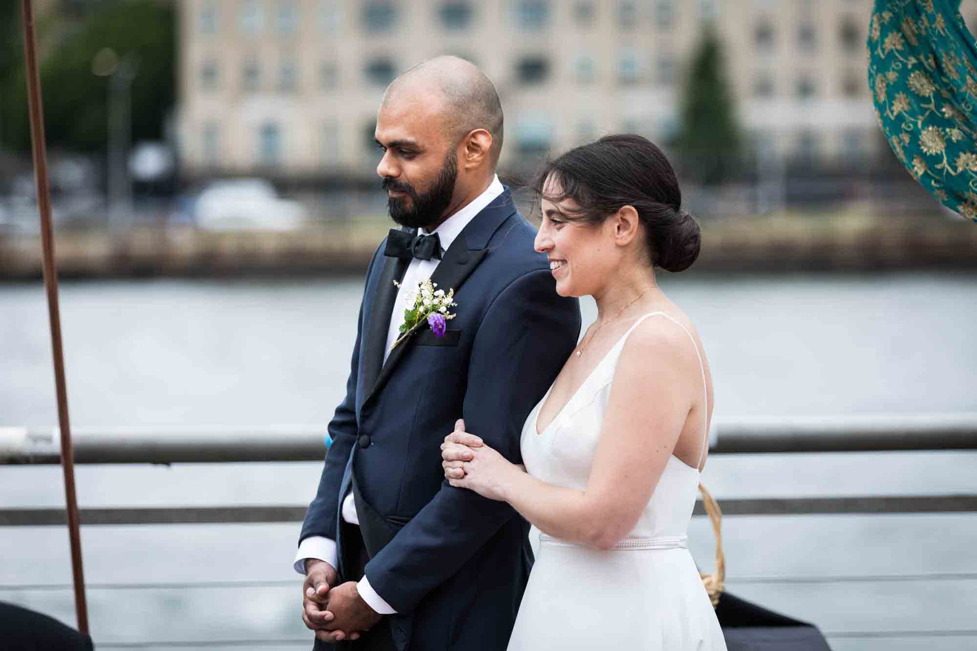 Bride holding groom's arm during outdoors ceremony at a Sanctuary Roosevelt Island wedding
