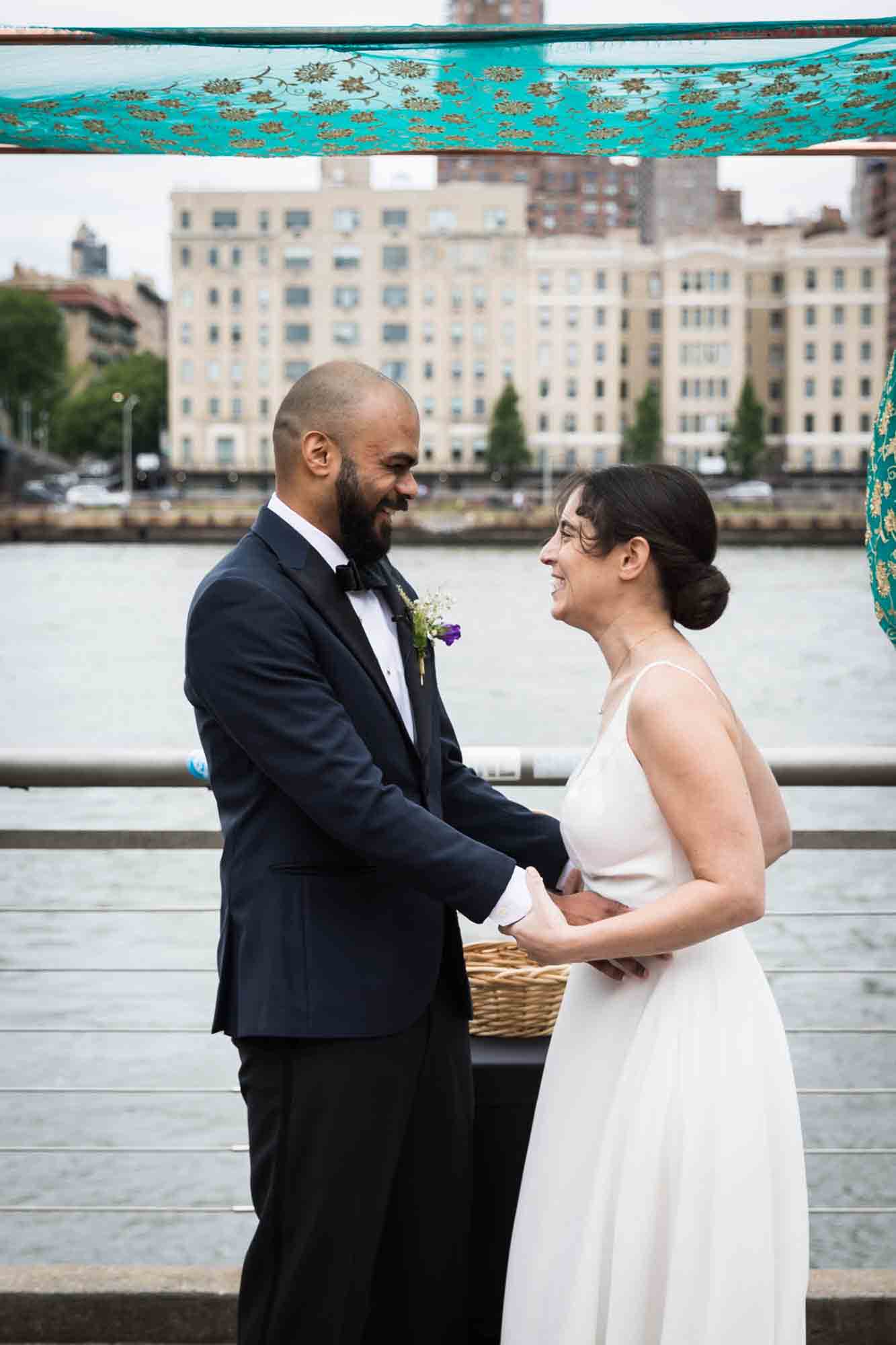 Bride and groom holding hands and laughing after outdoors ceremony at a Sanctuary Roosevelt Island wedding
