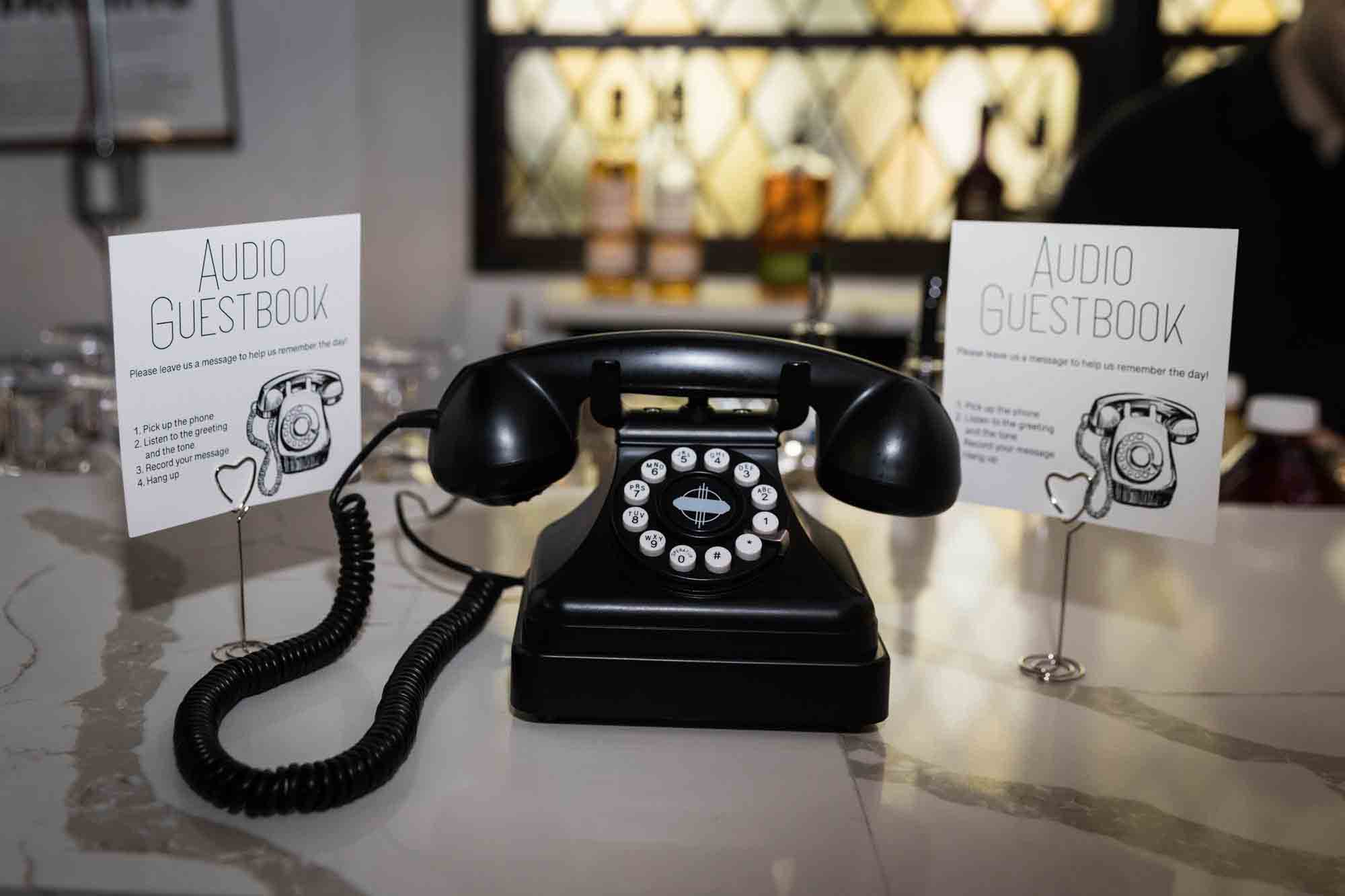 Black antique phone in front of two audio guestbook signs at a Sanctuary Roosevelt Island wedding